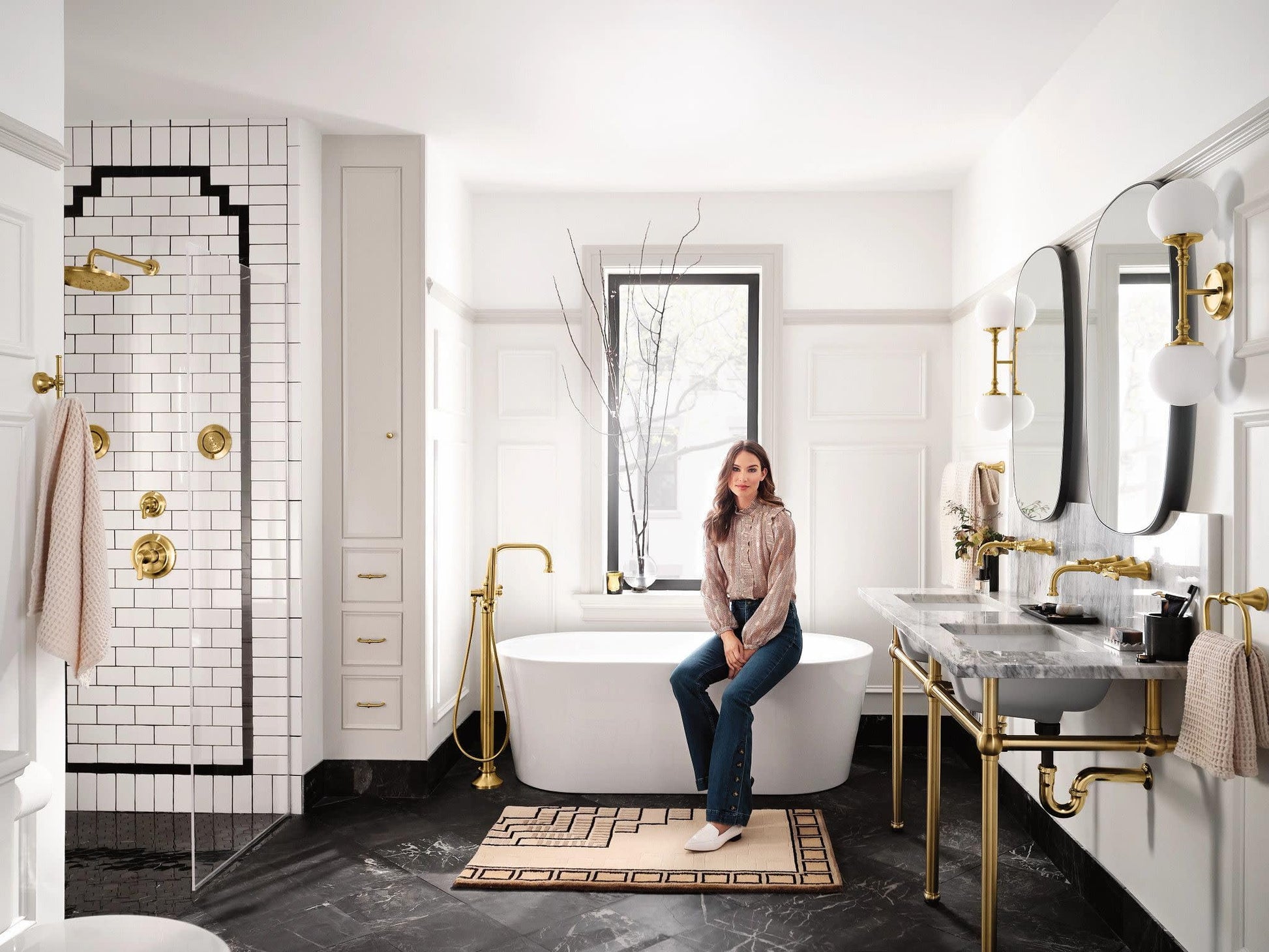 Brushed gold freestanding tub filler with single handle and attached handshower, floor-mounted beside white soaking tub.