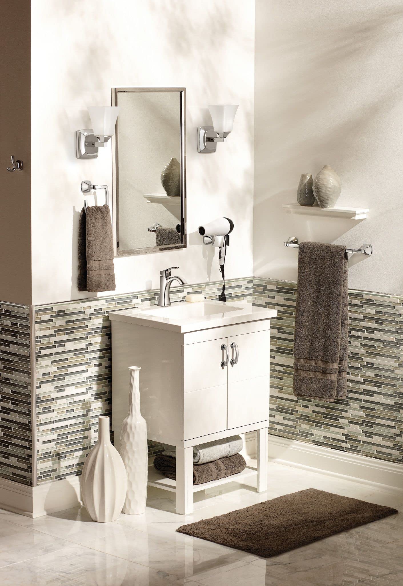 Chrome wall-mount towel ring installed on white bathroom wall beside mirror and sink vanity.