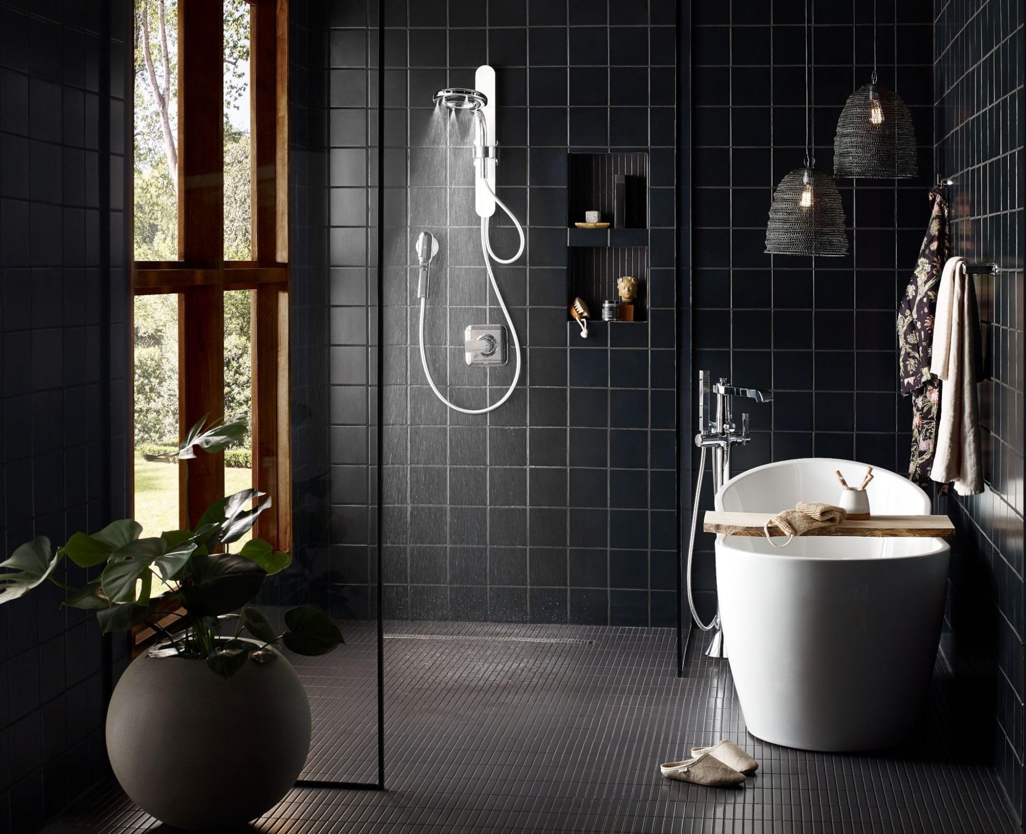 Chrome freestanding tub filler with single handle and detachable handshower mounted on bathroom wall above white soaking tub.