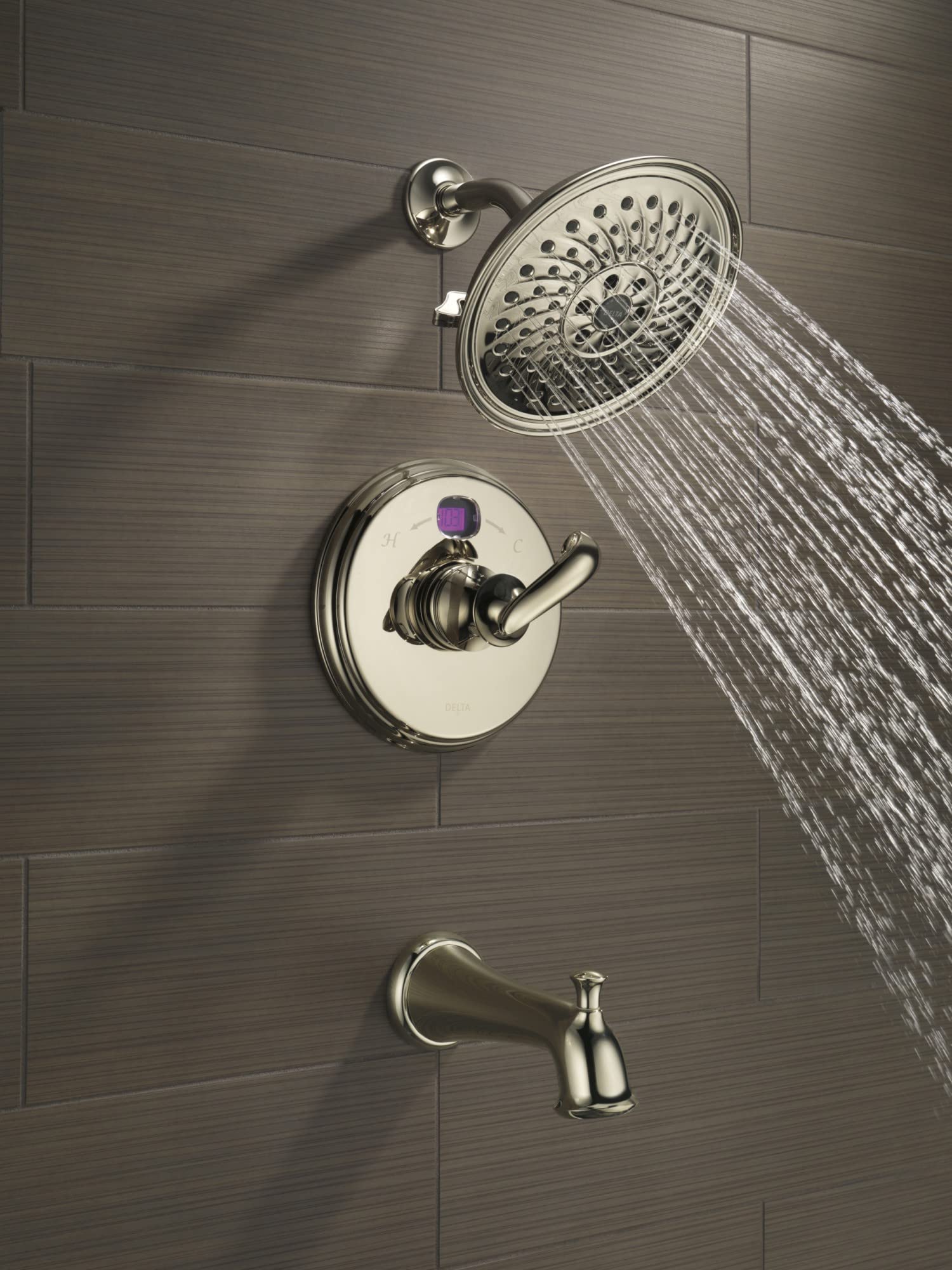 Chrome tub spout with pull-up diverter mounted on tile wall below showerhead and control valve.