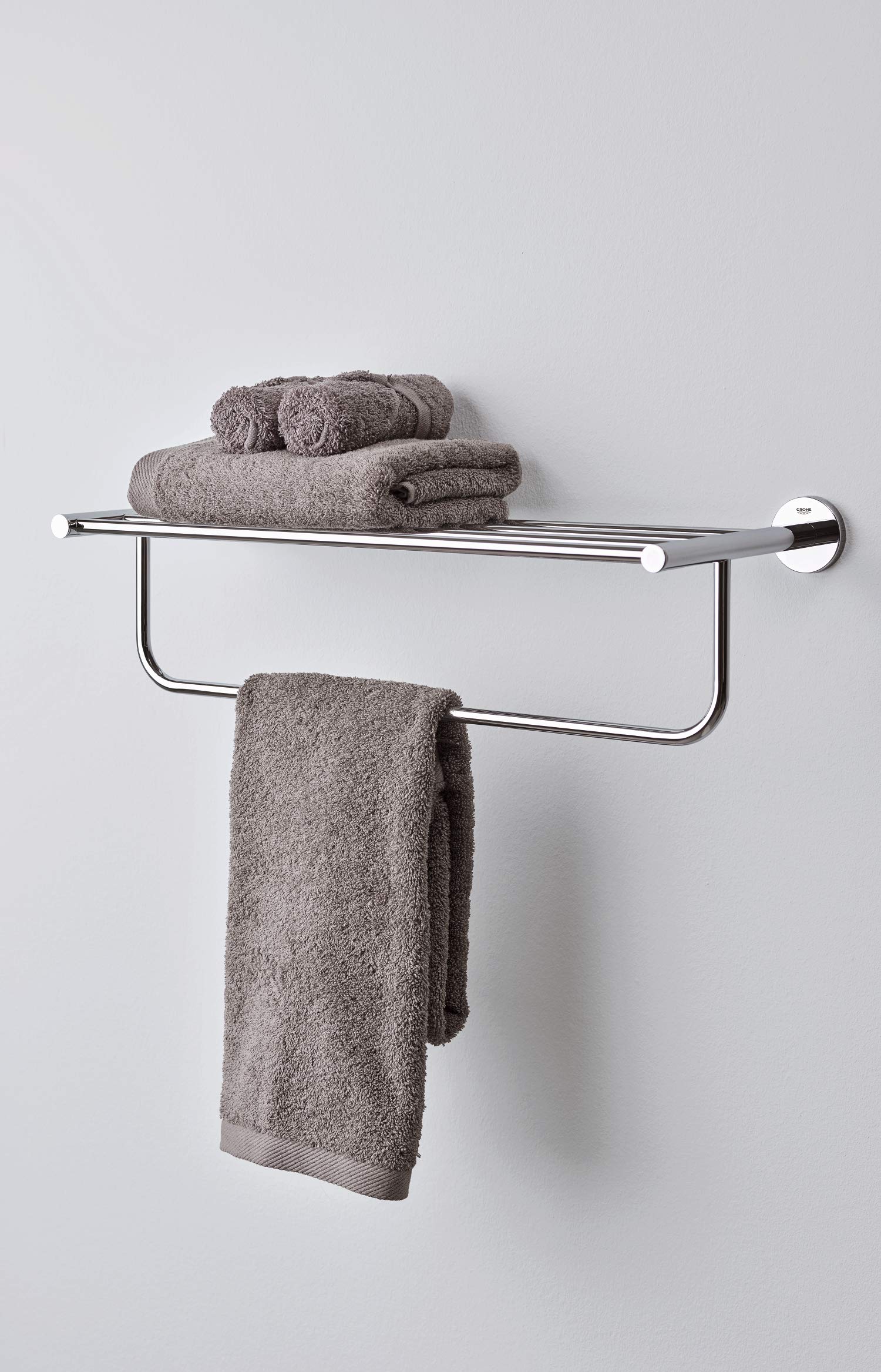 Chrome wall-mounted towel rack with upper shelf and lower bar, holding gray towels.