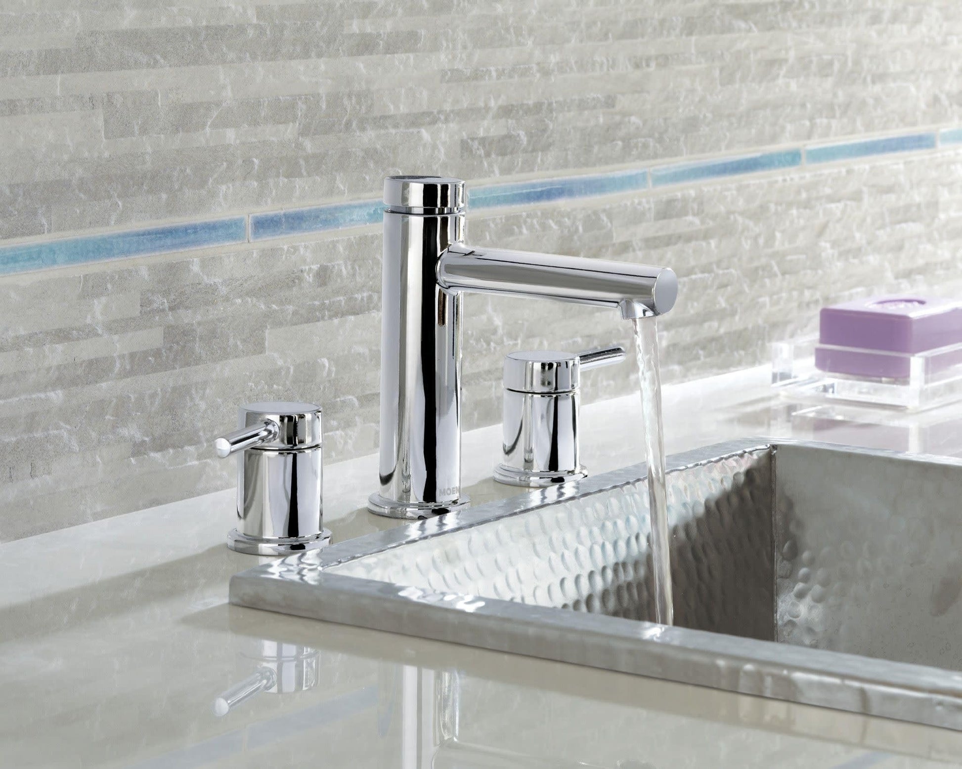 Chrome two-handle widespread bathroom faucet with cylindrical handles and arcing spout installed on sink countertop.