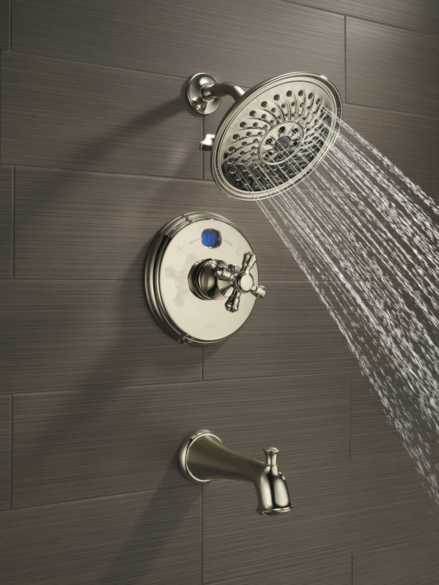 Chrome tub spout with pull-up diverter mounted on tile wall below showerhead and valve trim.