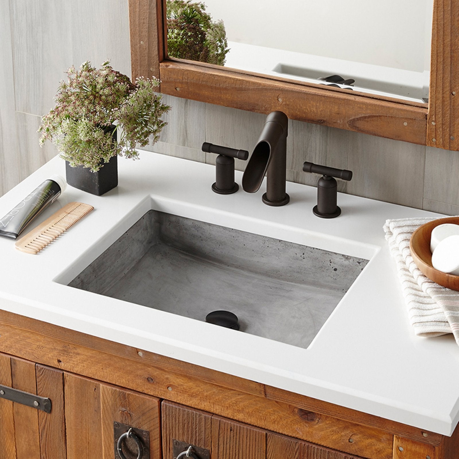 Slate-colored rectangular bathroom sink with white countertop and black faucet fixtures installed in wooden vanity.
