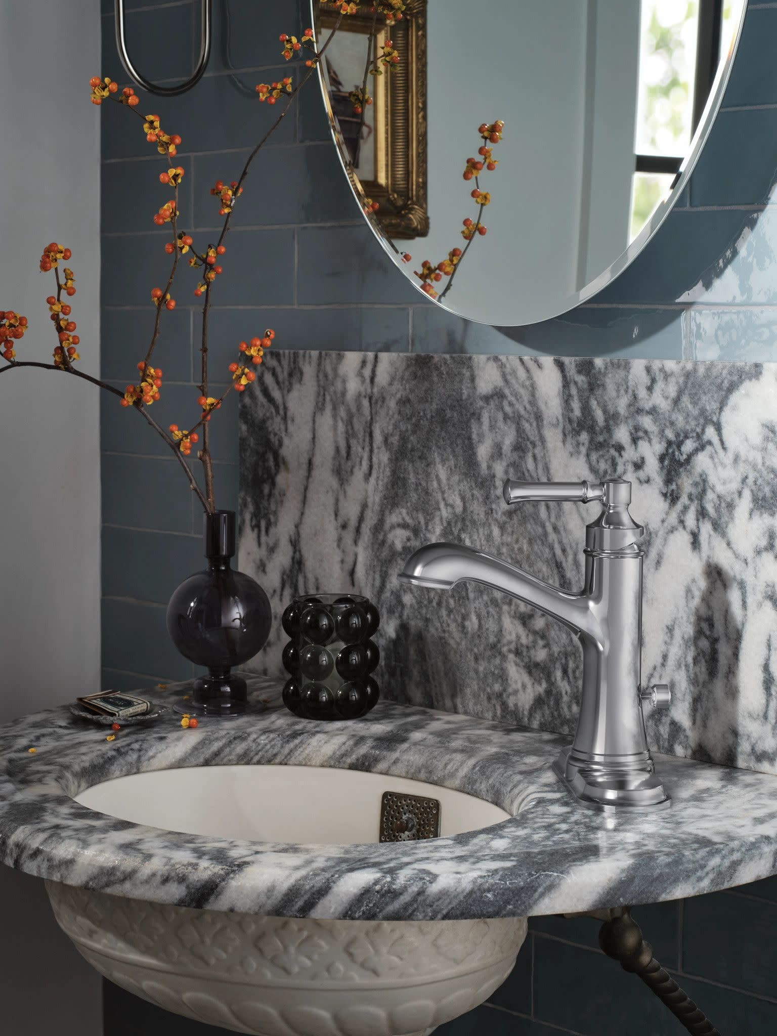 Chrome single-handle bathroom faucet with curved spout installed on marble countertop sink.