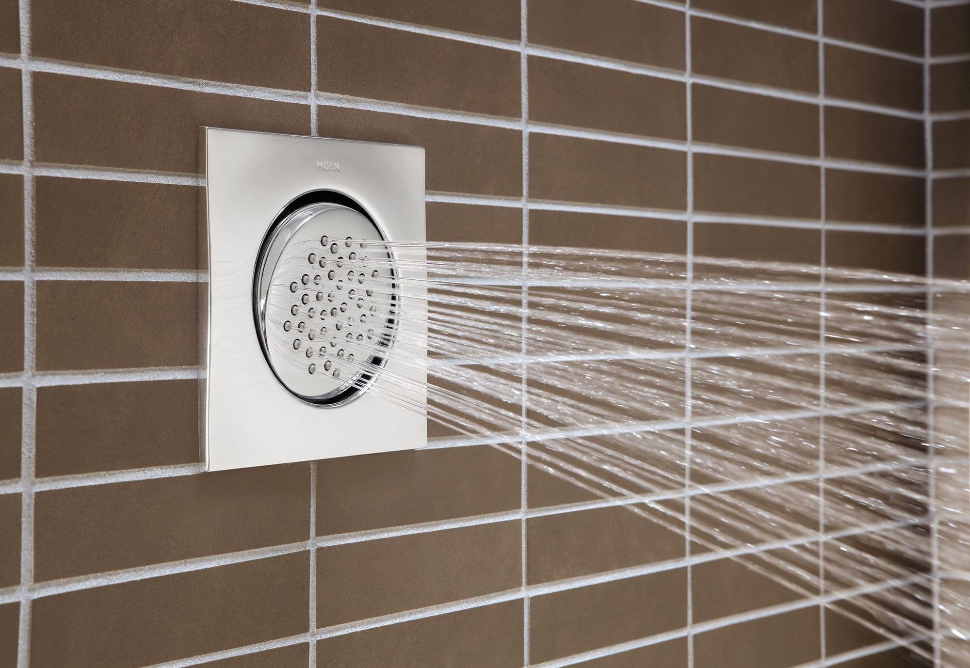 Polished nickel square body spray mounted on tile wall with water stream spraying.