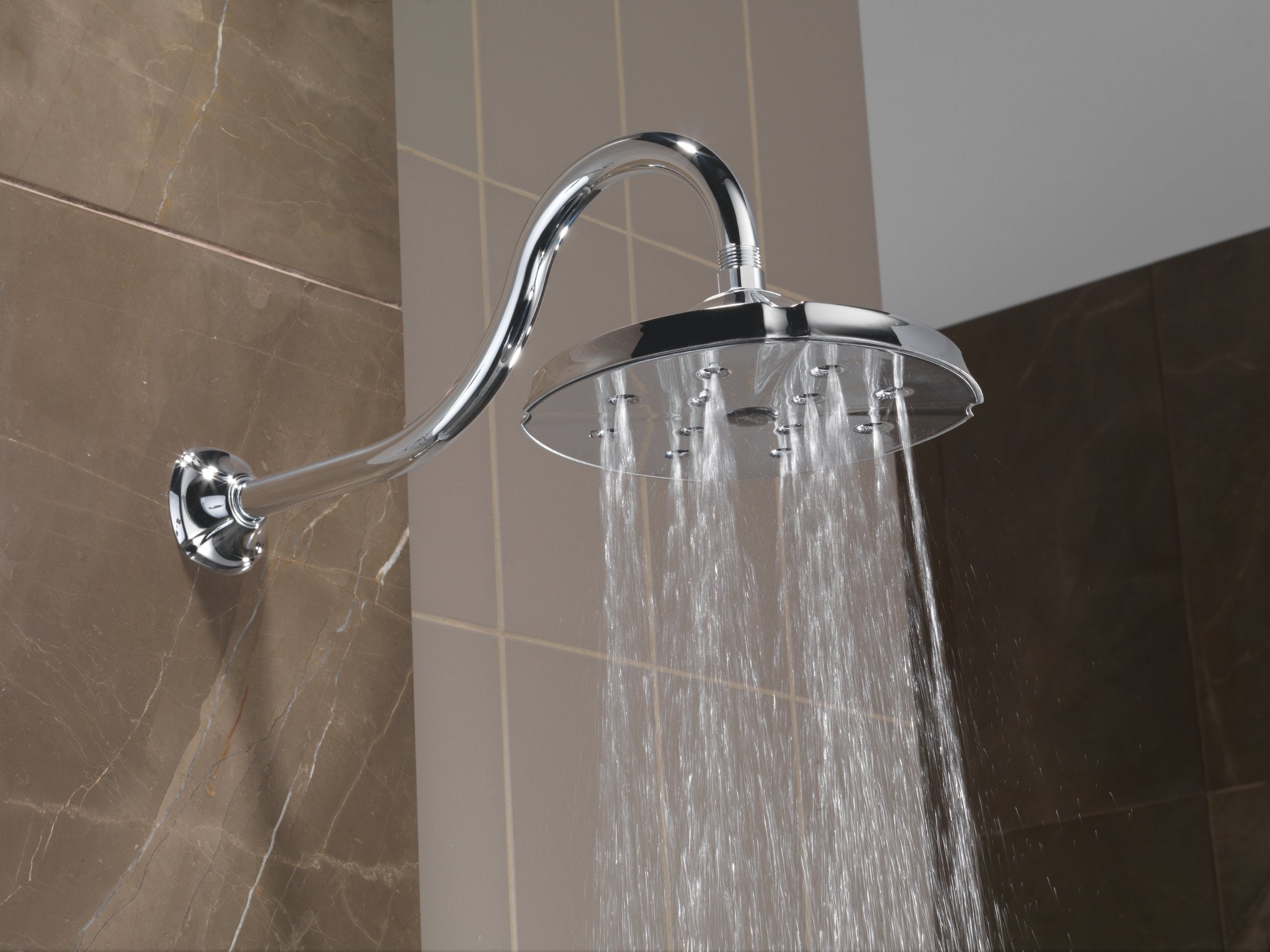 Chrome shower arm with curved gooseneck design and round showerhead, mounted on tiled bathroom wall.