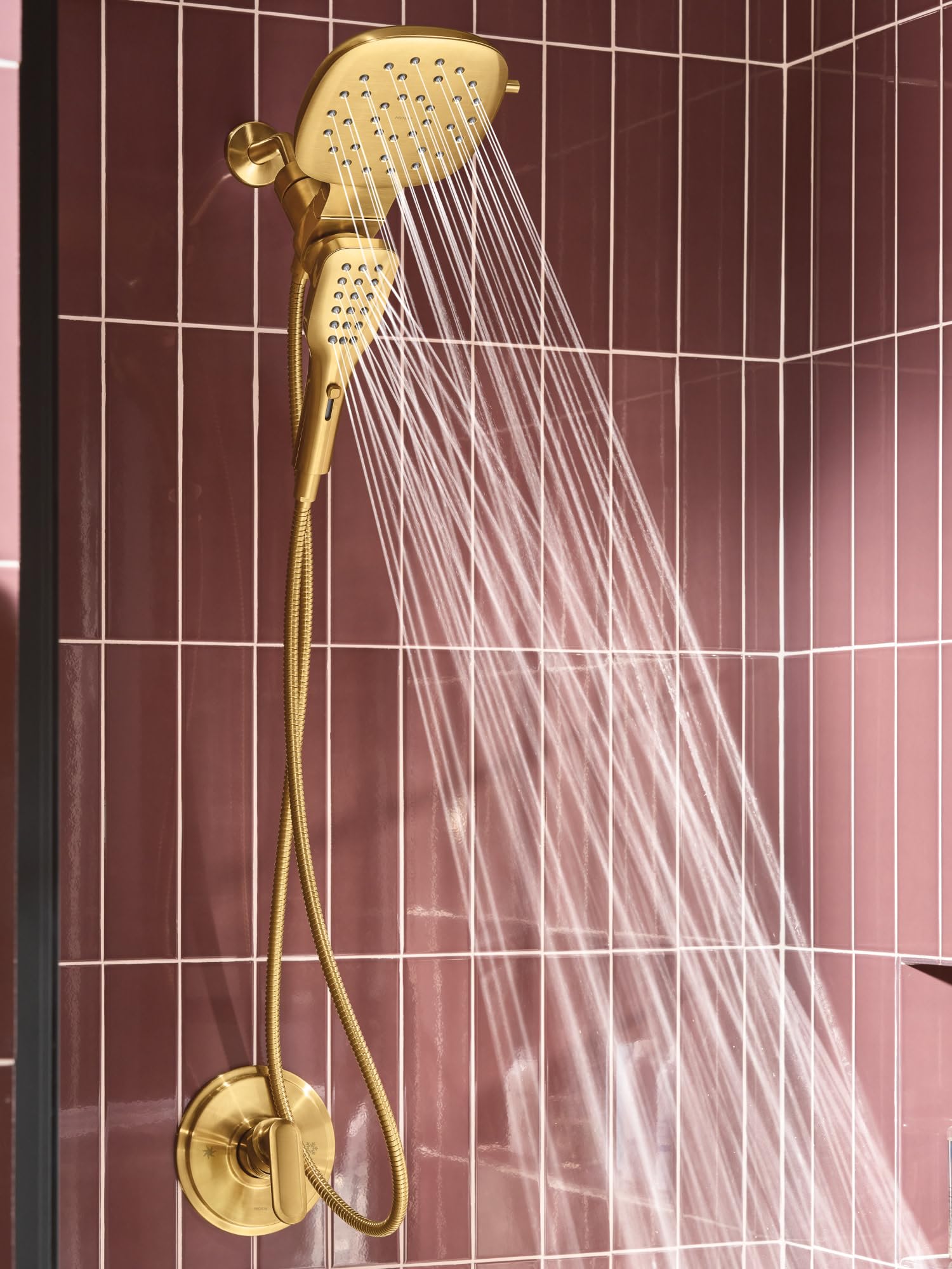 Brushed gold square rain shower head with detachable hand shower and dual control dial mounted on tiled bathroom wall.