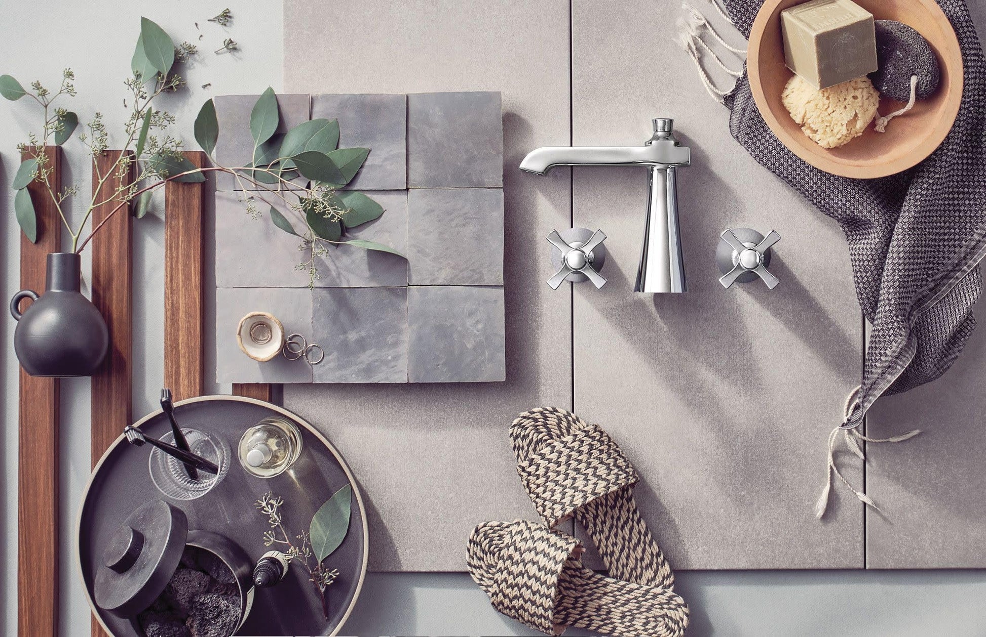 Chrome bathroom faucet with tall spout and two cross handles mounted on gray tile wall.
