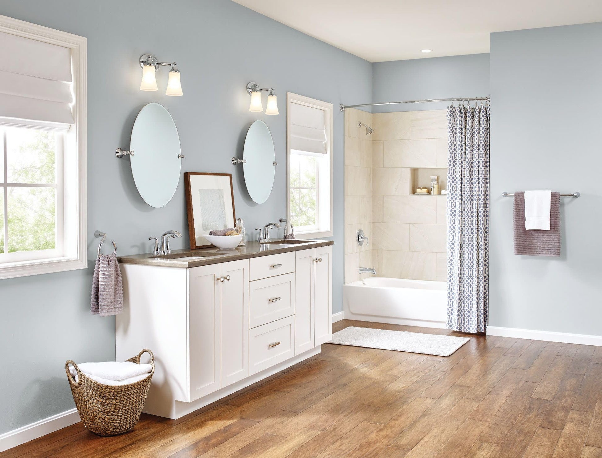 Chrome two-handle high arc centerset bathroom faucet mounted on dual sink vanity with white cabinetry.