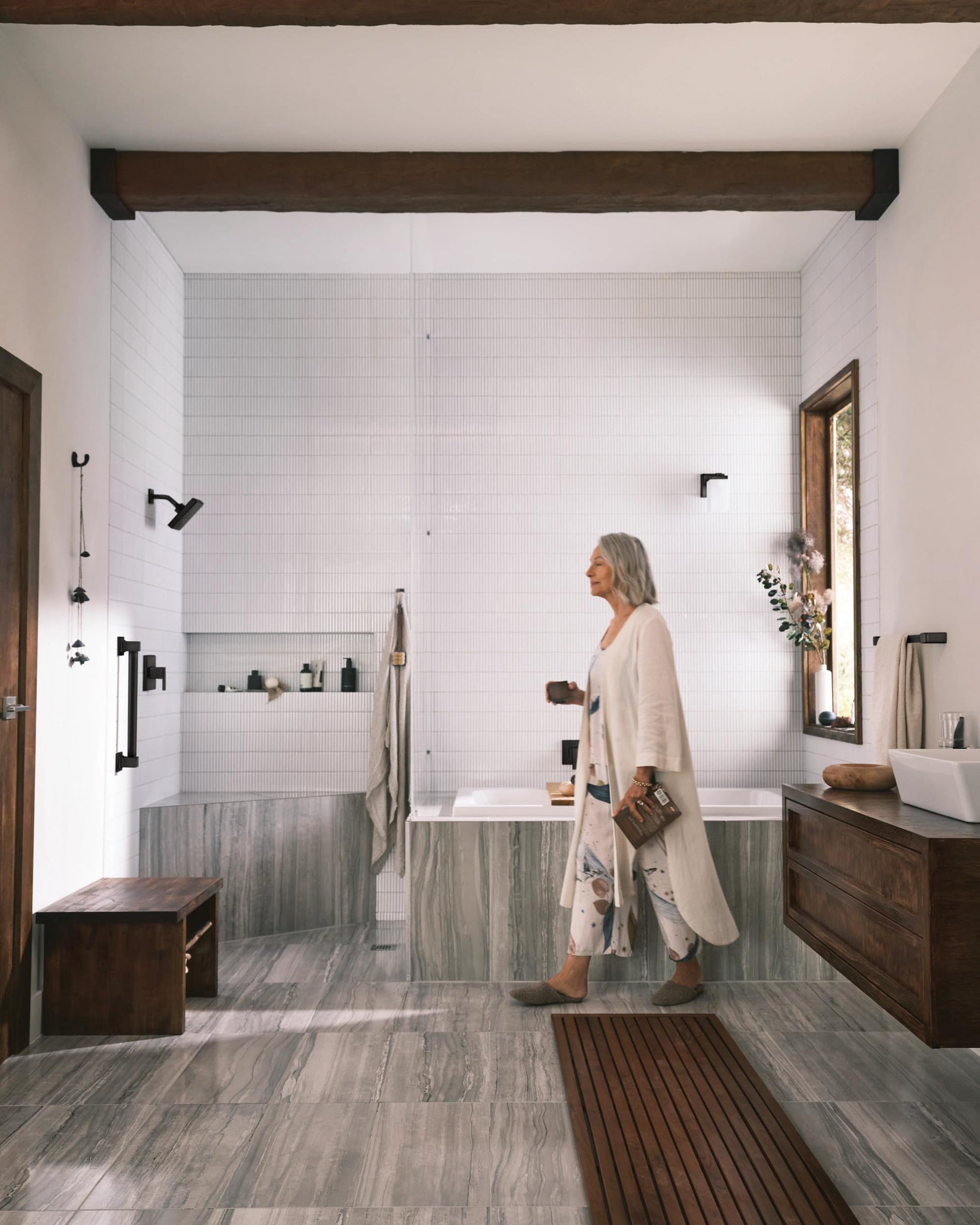 Matte black single-handle shower trim with showerhead and controls mounted on white subway tile bathroom wall.