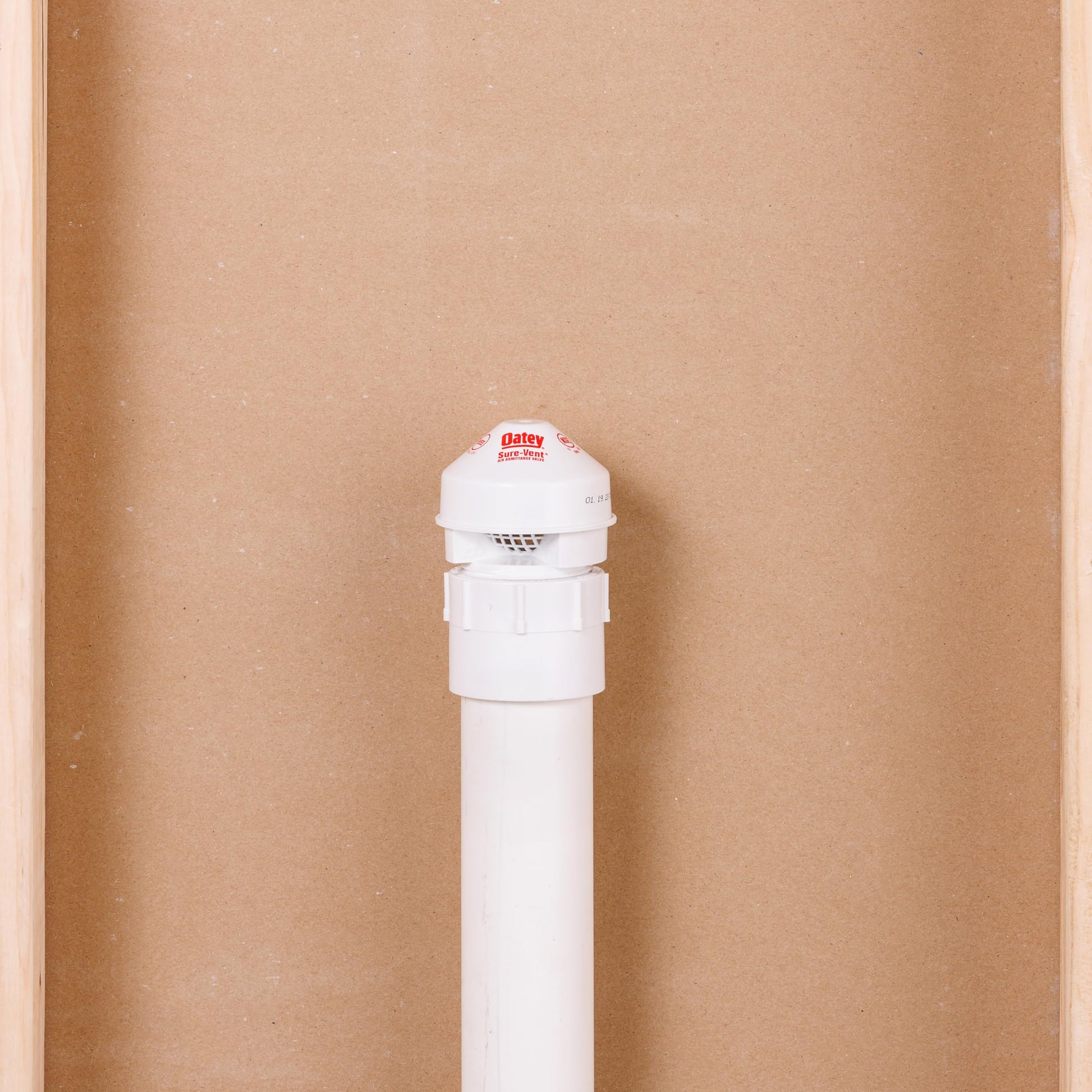 White PVC air admittance valve with domed cap and threaded adapter, shown vertically against cardboard background.