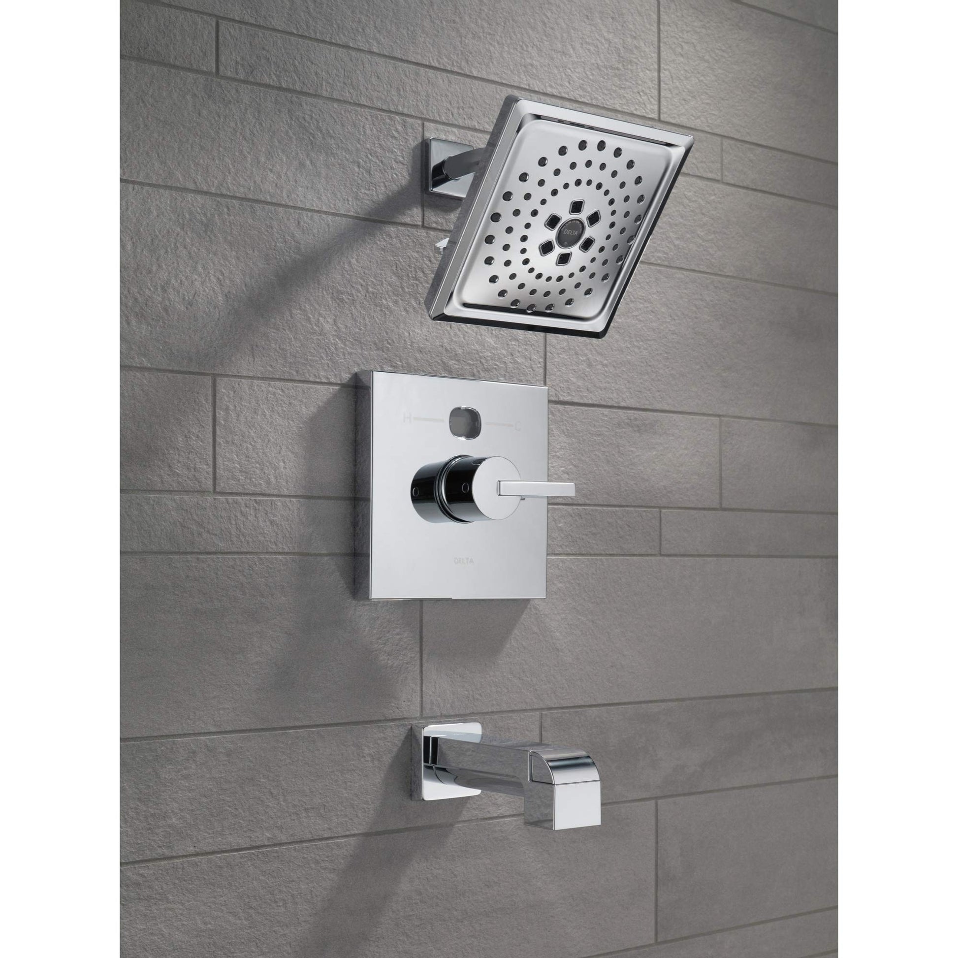 Chrome tub spout with pull-up diverter mounted on tile wall below showerhead and control valve.