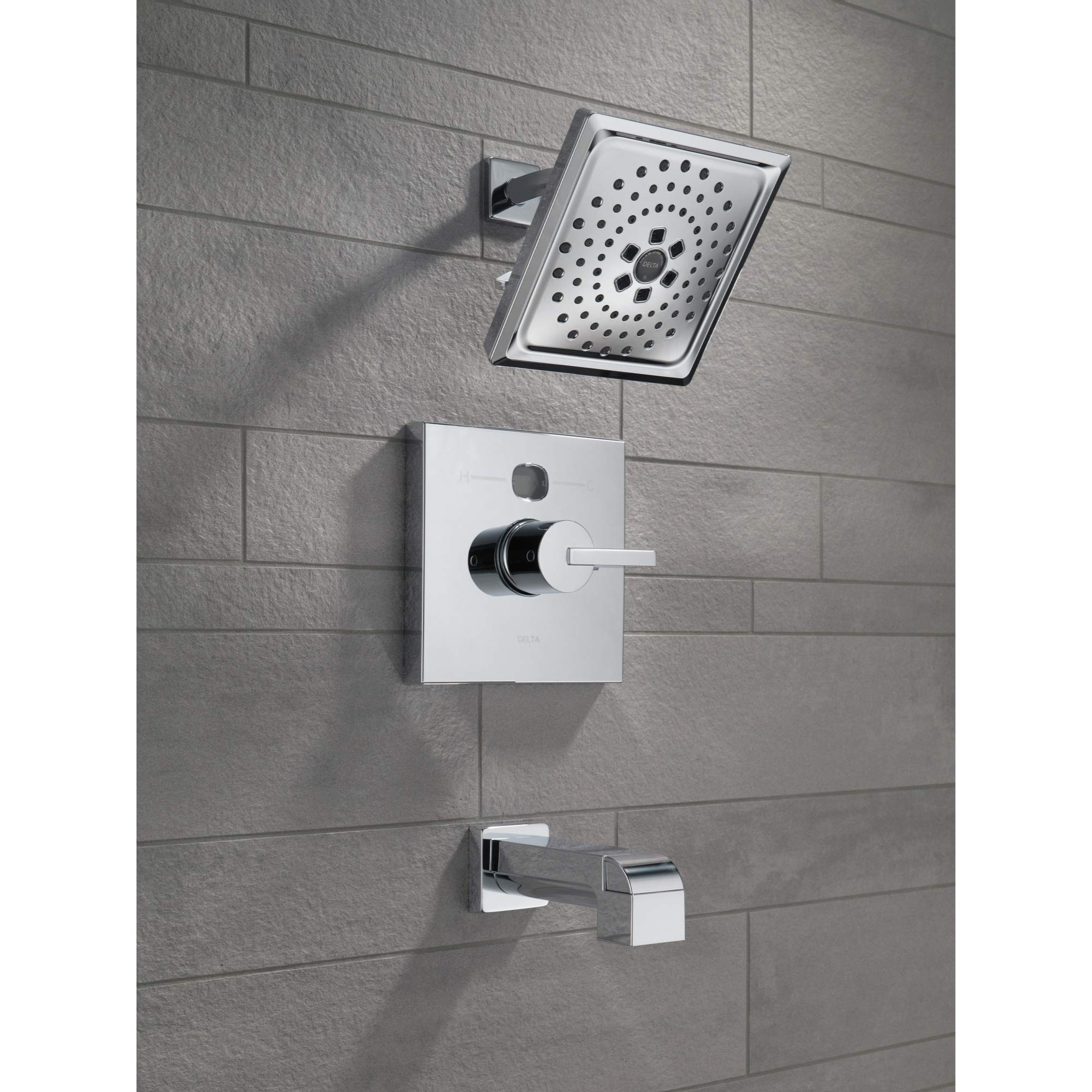 Matte black tub spout with pull-up diverter mounted on gray tile wall with matching showerhead and control valve above.