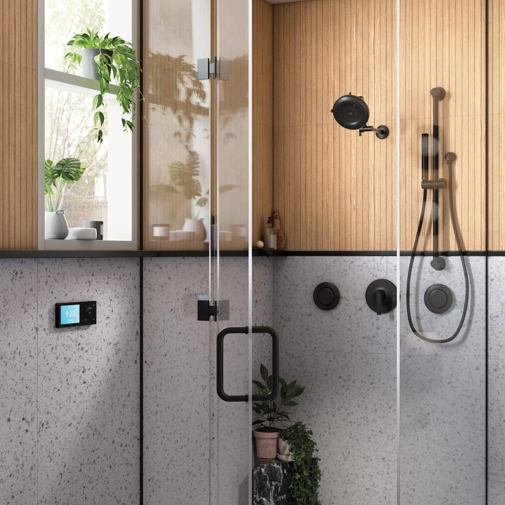 Matte black handheld shower with slide bar and metal hose mounted on gray tile bathroom wall.