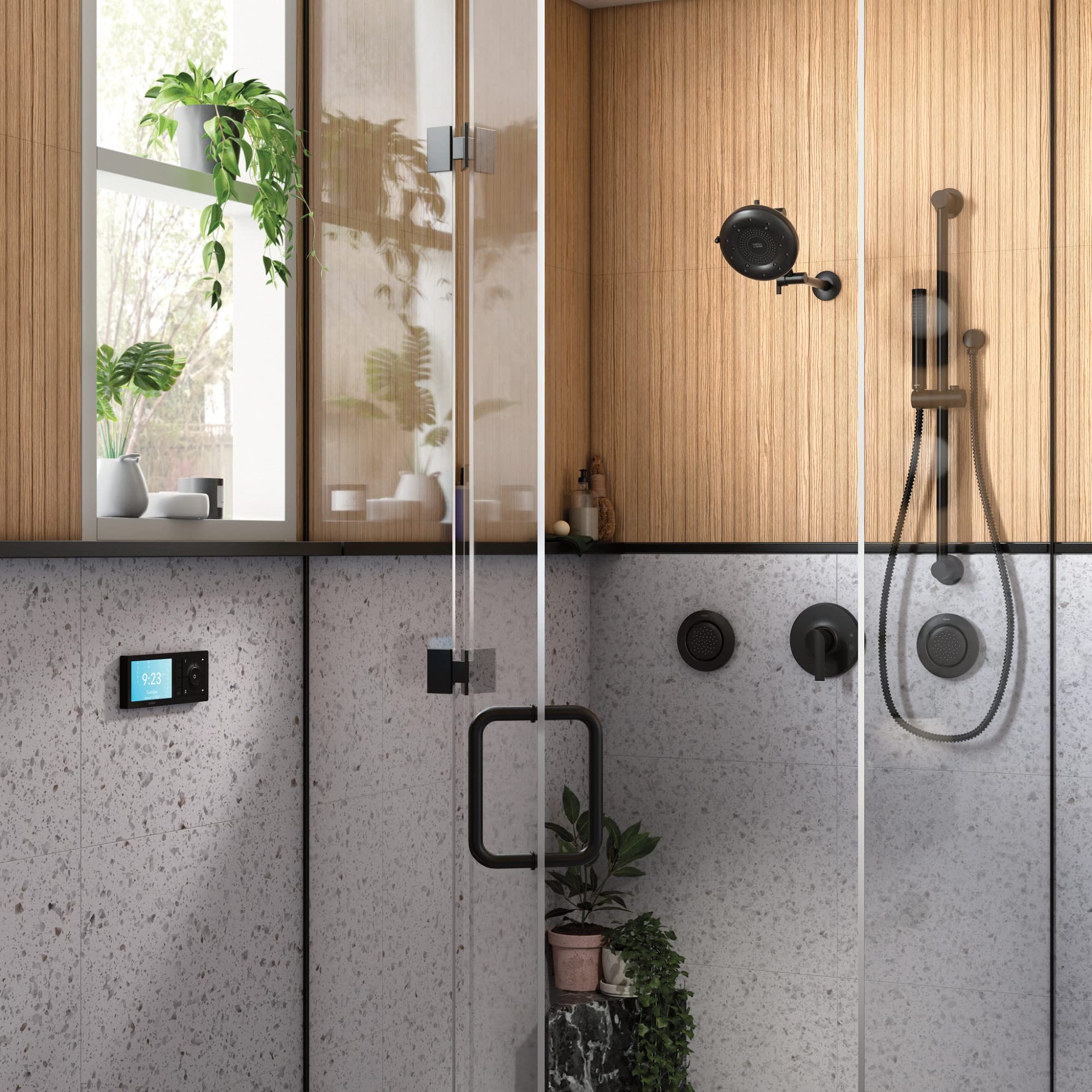 Matte black handheld shower with slide bar and metal hose mounted on gray tile bathroom wall.