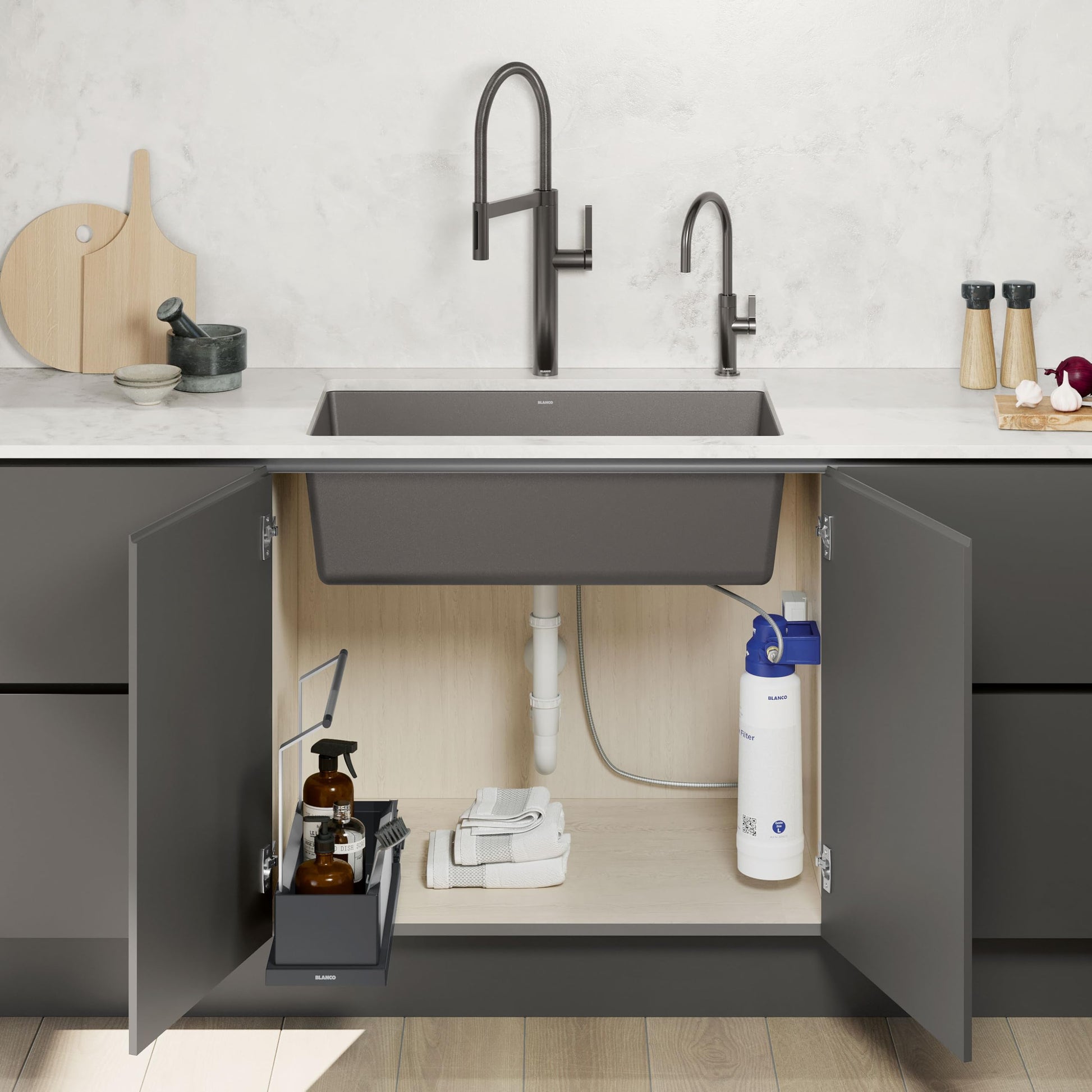 Black storage caddy with compartments positioned under sink, holding cleaning supplies and bottles.