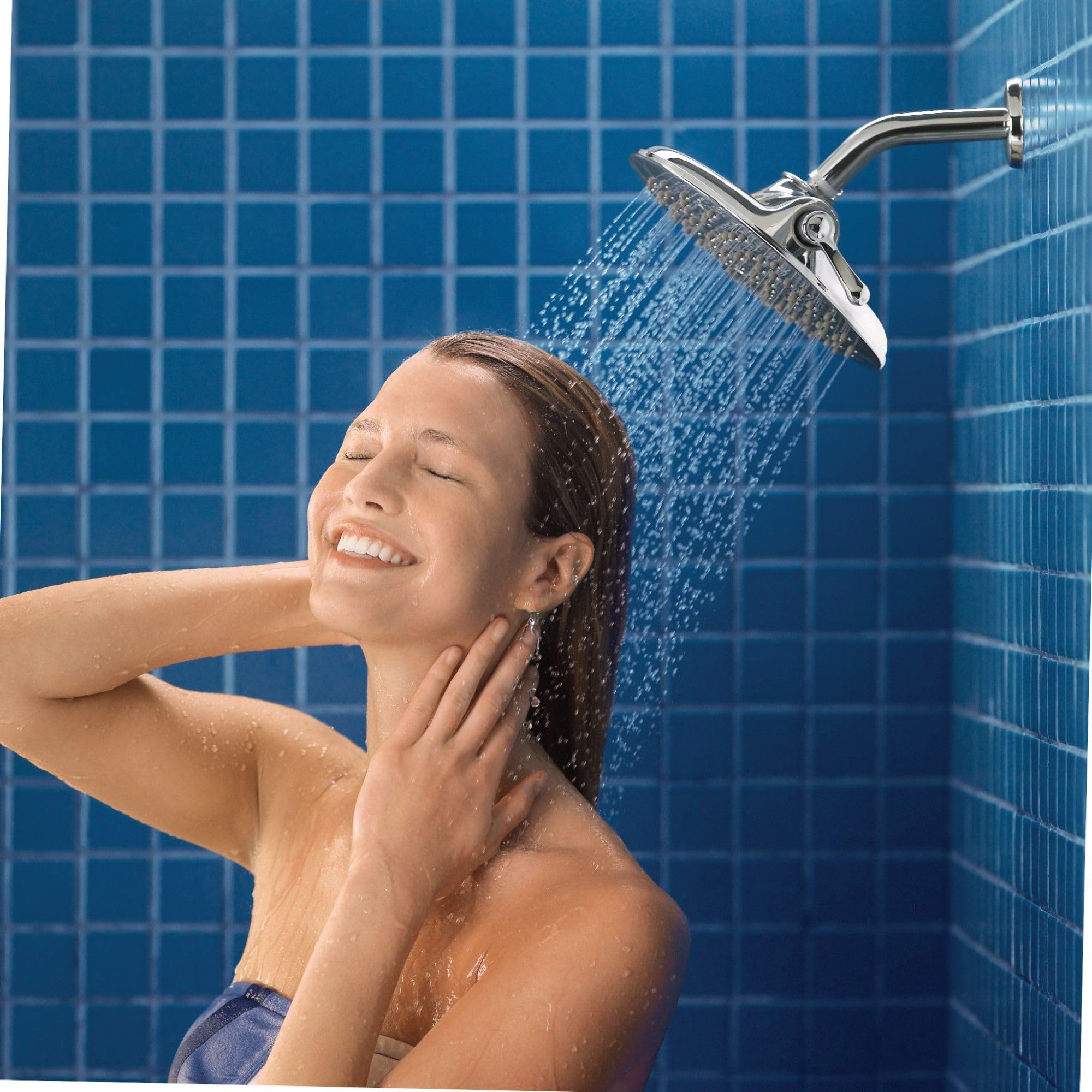 Chrome rainshower head mounted on wall with curved arm, dispensing water onto person below in blue tiled shower.