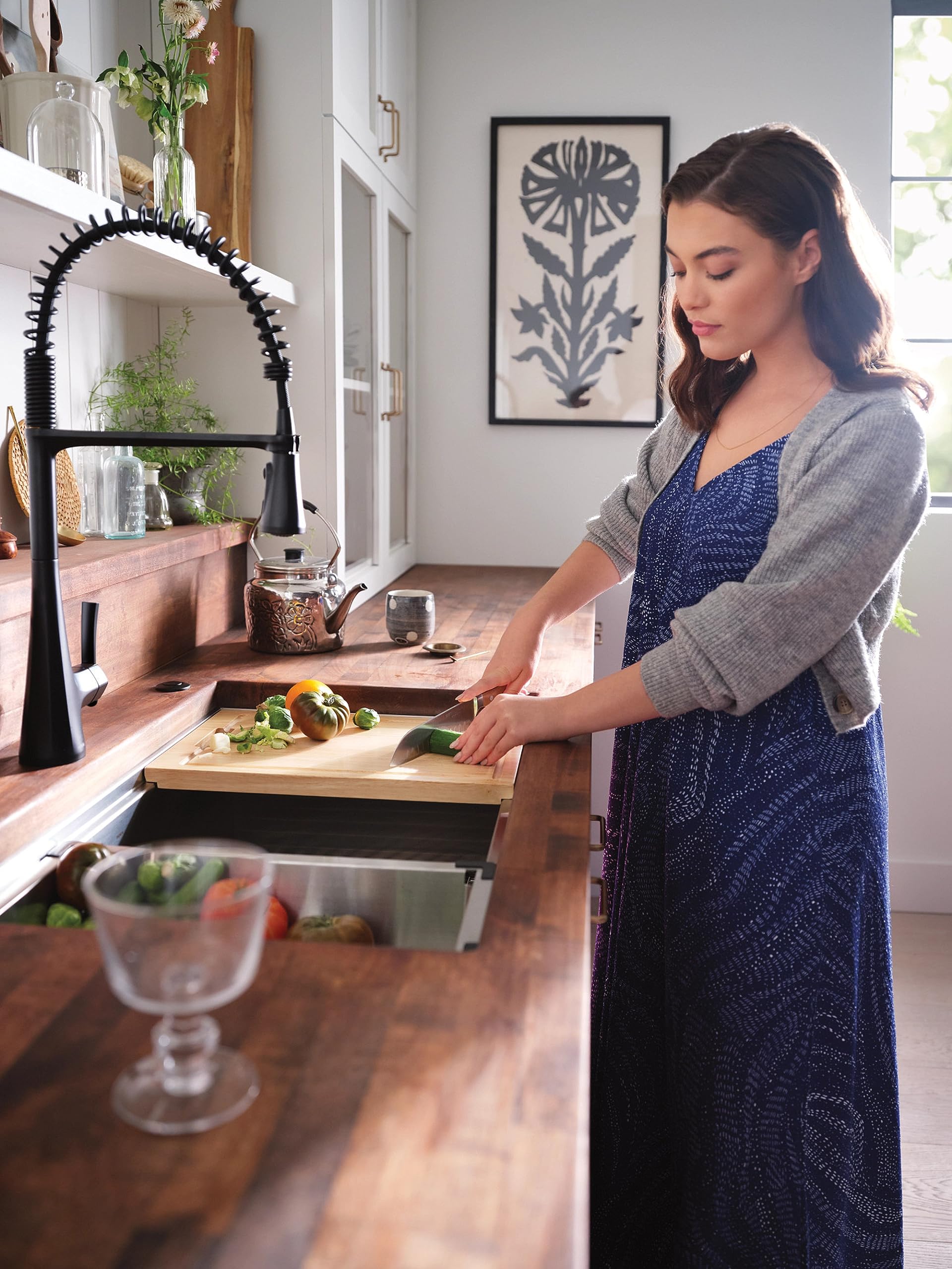 Matte black single-handle pulldown kitchen faucet with coiled spray hose over wooden countertop sink.