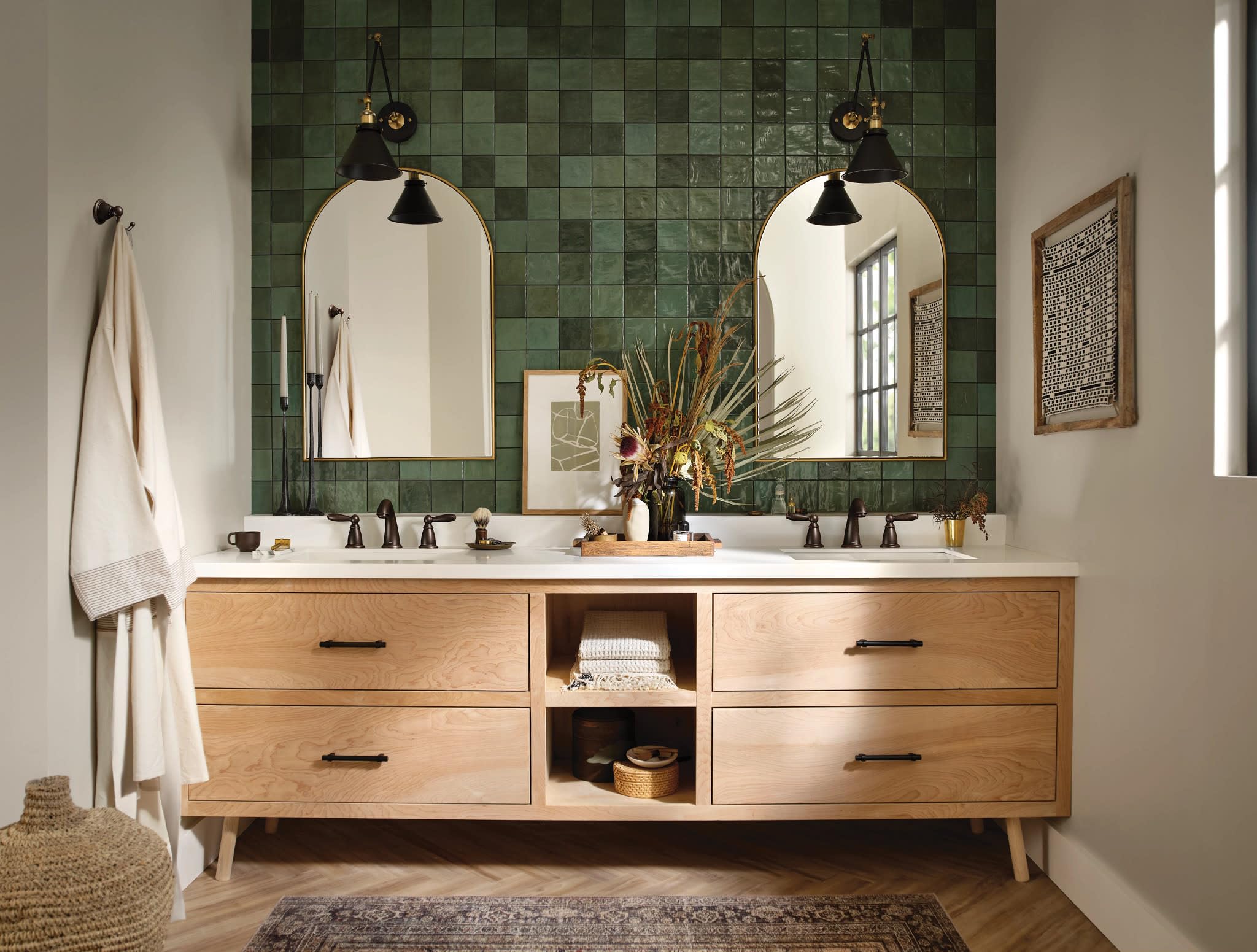 Oil rubbed bronze two-handle widespread faucet trim with curved spout installed on double sink vanity.