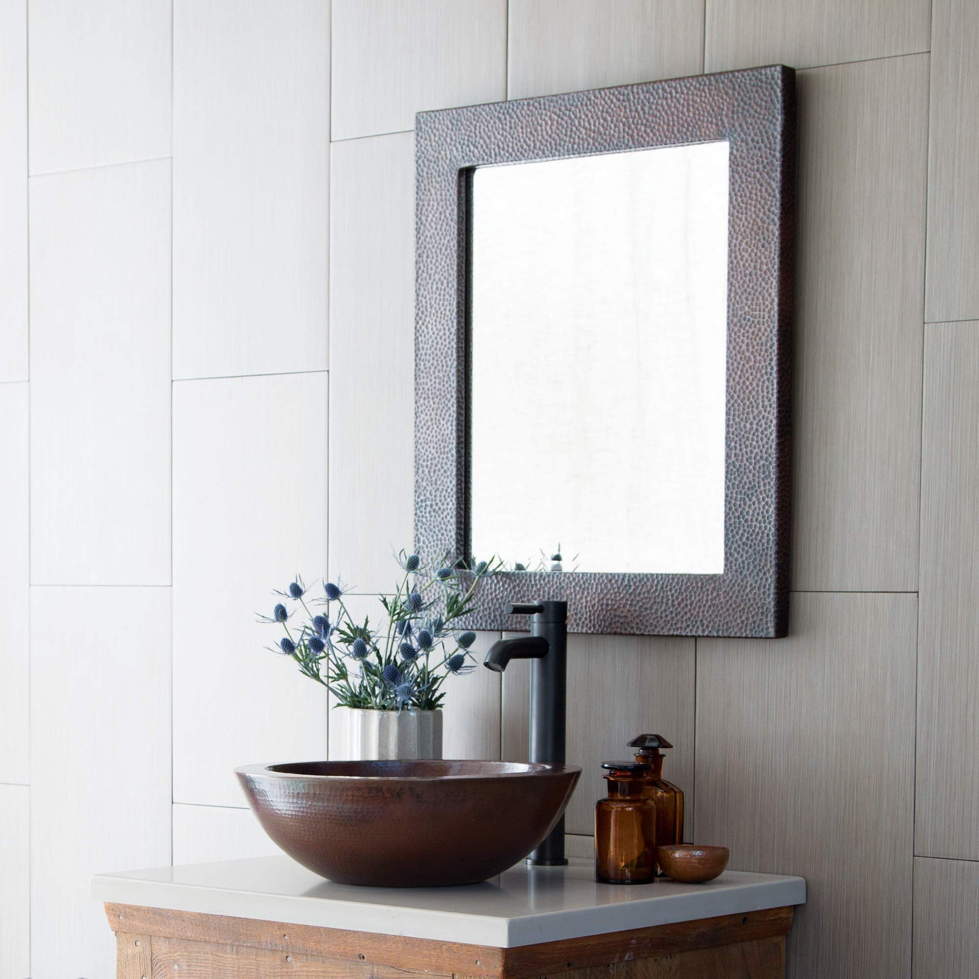 Antique copper rectangle mirror with hammered texture frame mounted above bathroom vanity with copper vessel sink.
