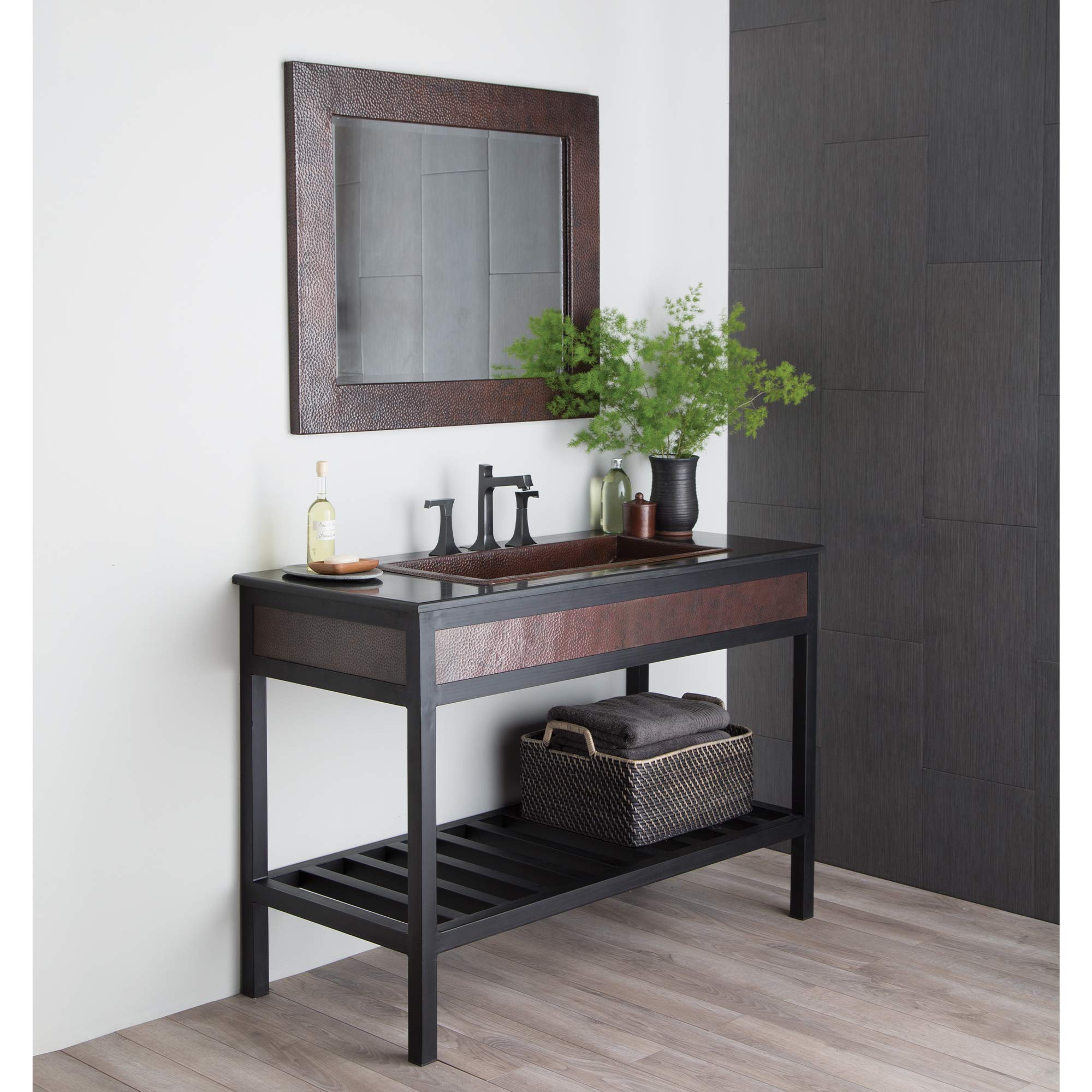 Rectangular mirror with textured antique copper-finish frame hung above bathroom vanity.