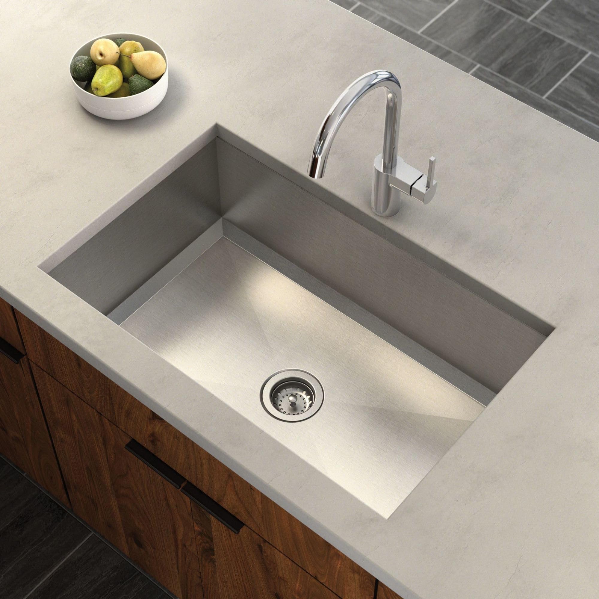 Stainless steel single-bowl undermount kitchen sink installed in light countertop with chrome faucet.