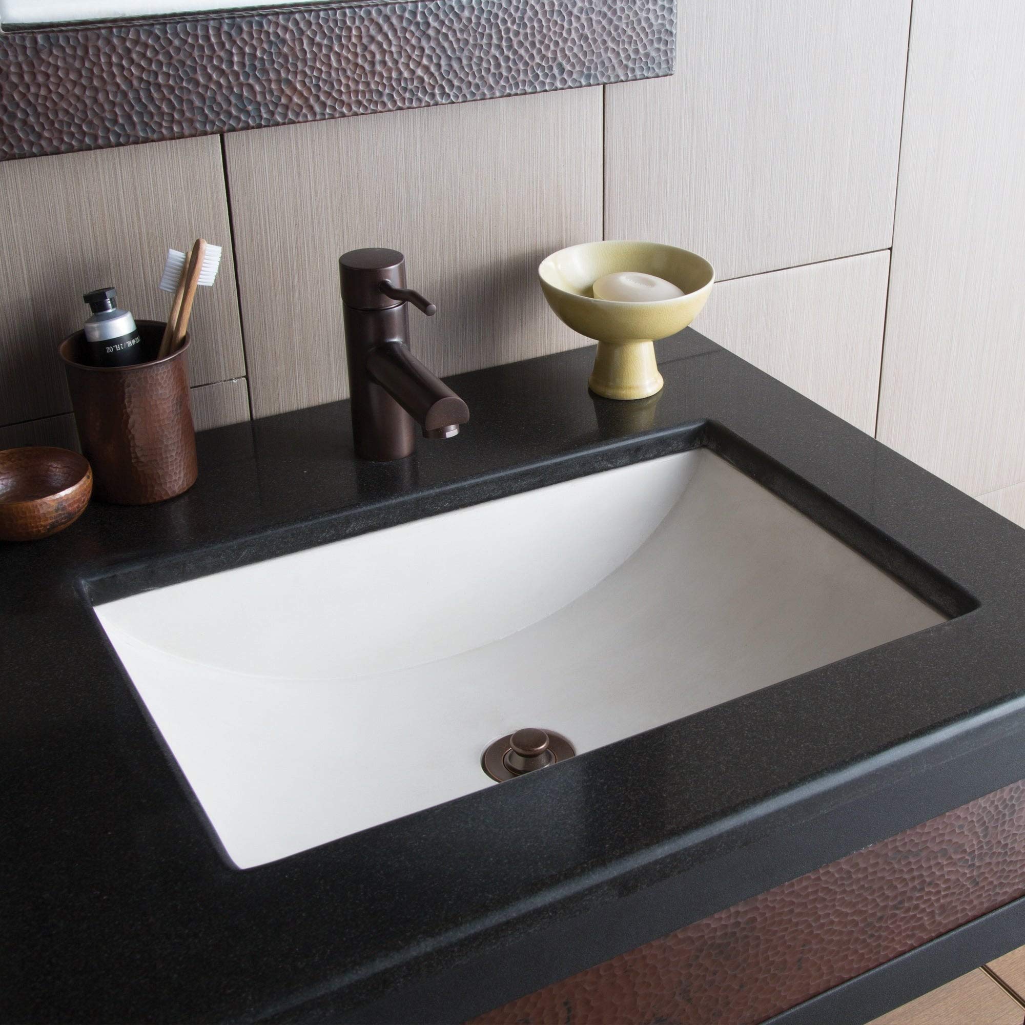 White rectangular undermount bathroom sink with curved interior walls installed in dark countertop.
