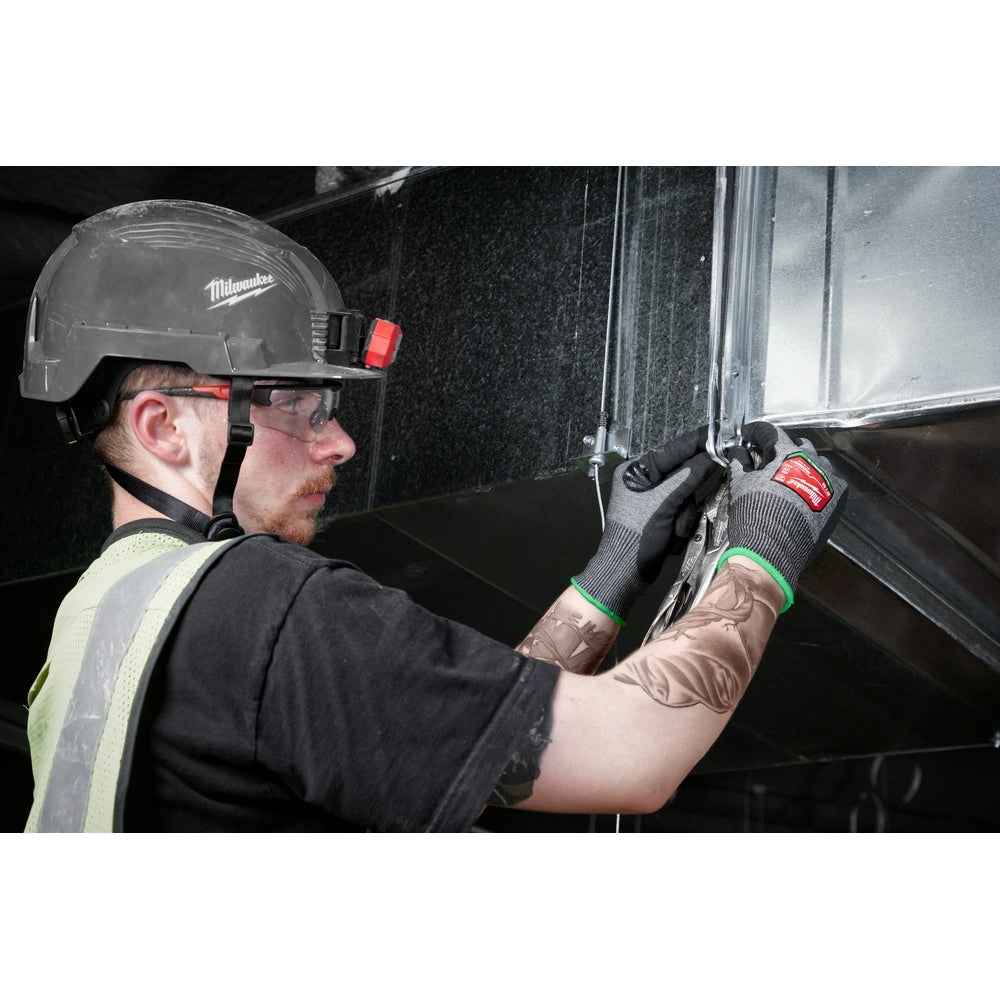 Black nitrile dipped work gloves with gray knit exterior worn by worker handling metal sheet.