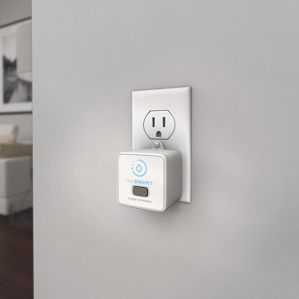 White leakSMART range extender device with blue logo mounted on wall outlet above standard electrical outlet.