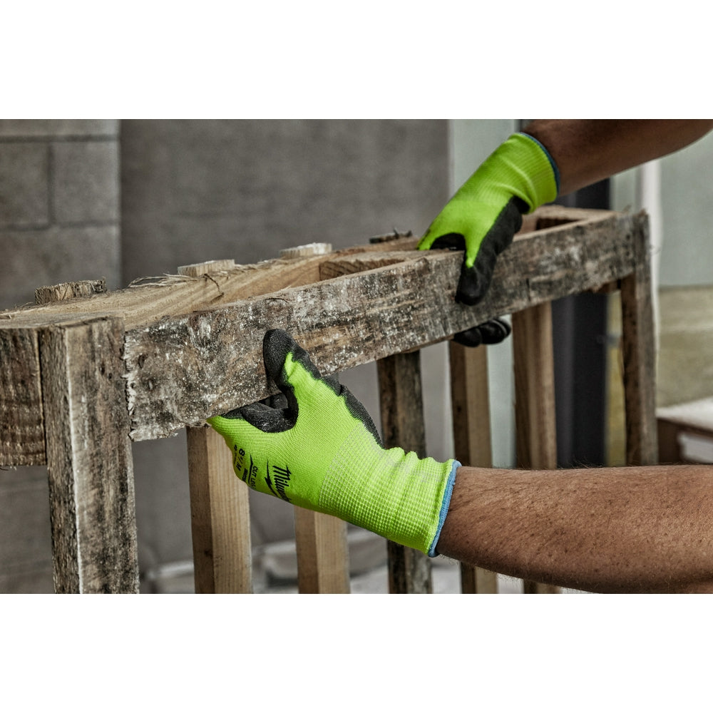 Yellow-green and black polyurethane-dipped work gloves being worn while gripping a rough wooden beam.