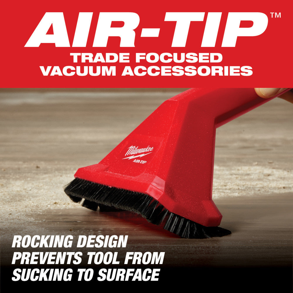 Red Milwaukee AIR-TIP utility nozzle with black bristle brush attachment on wooden surface.