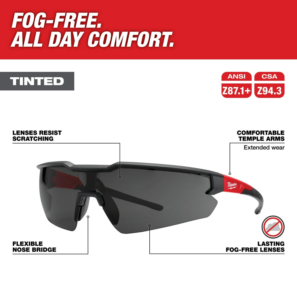 Milwaukee safety glasses with tinted gray lenses, black frames, and red temple arms featuring flexible nose bridge.