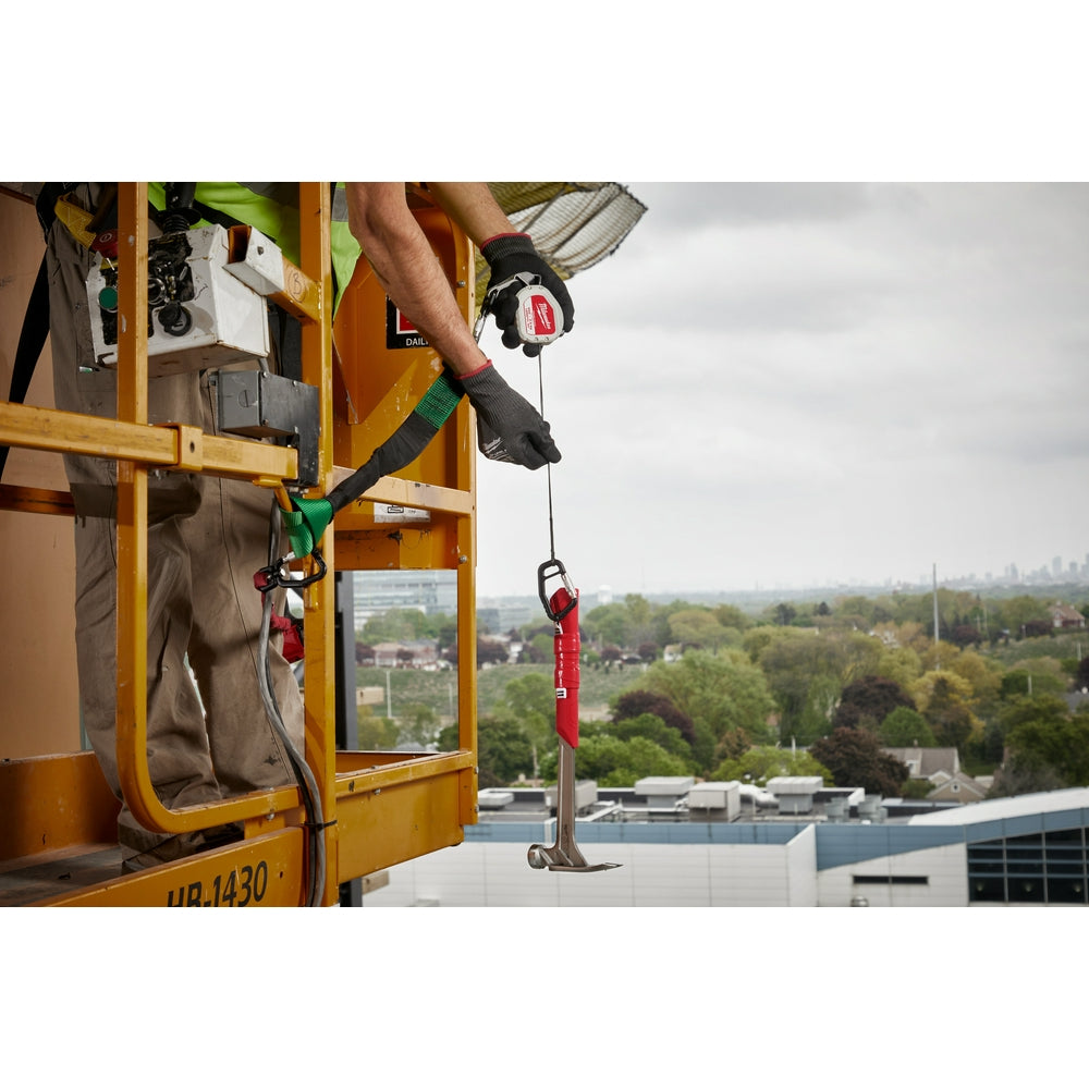 Black retractable tool lanyard with red carabiners extended from reel, attached to worker's belt on elevated platform.