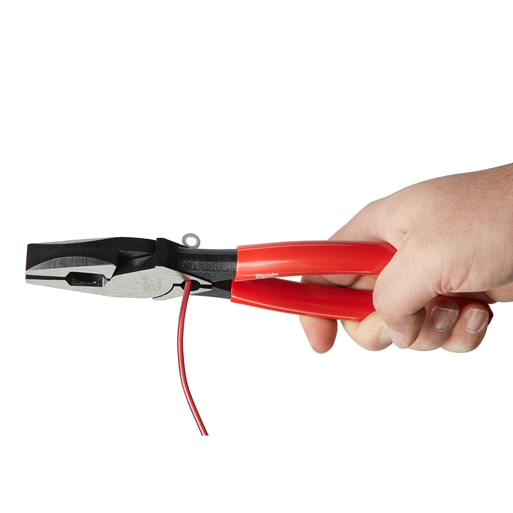 Linesman's pliers with red dipped handles held in hand, showing cutting and crimping jaws with red electrical wire.