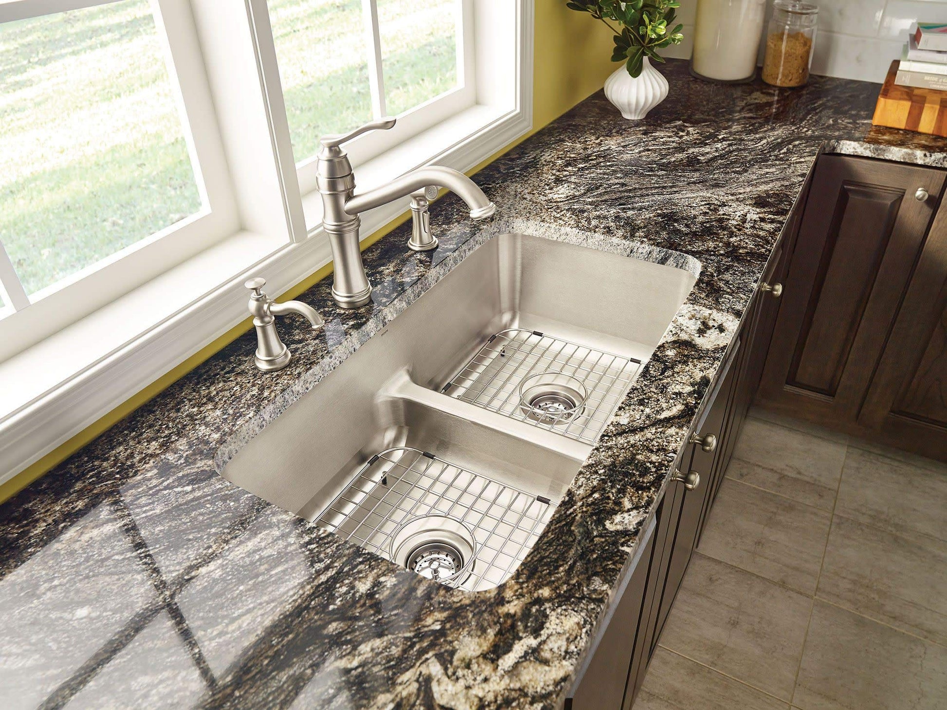 Stainless steel kitchen faucet with high arc spout and side spray installed above double undermount sink.