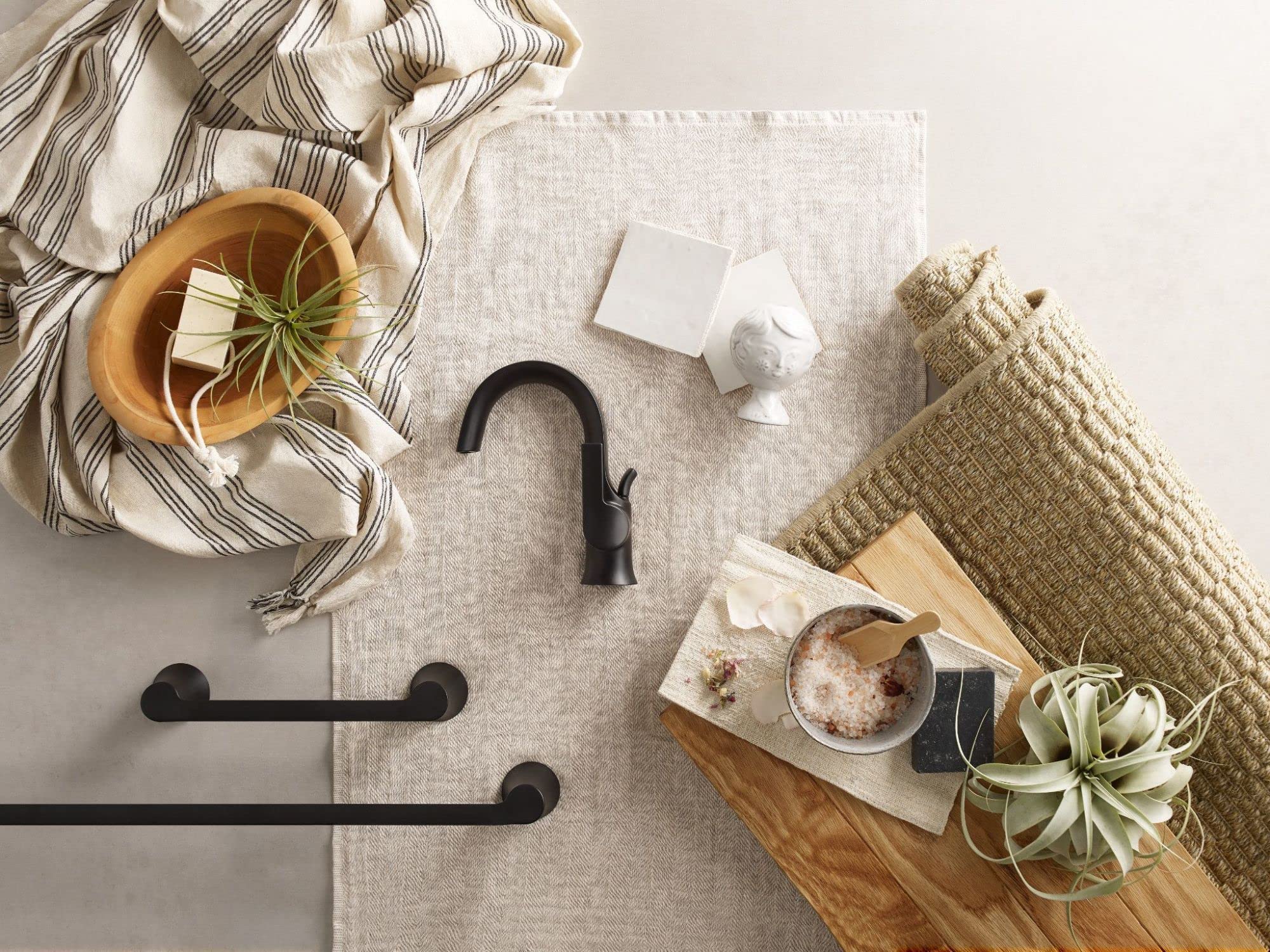 Matte black single-handle bathroom faucet with high arc spout displayed on neutral background with styling accessories.