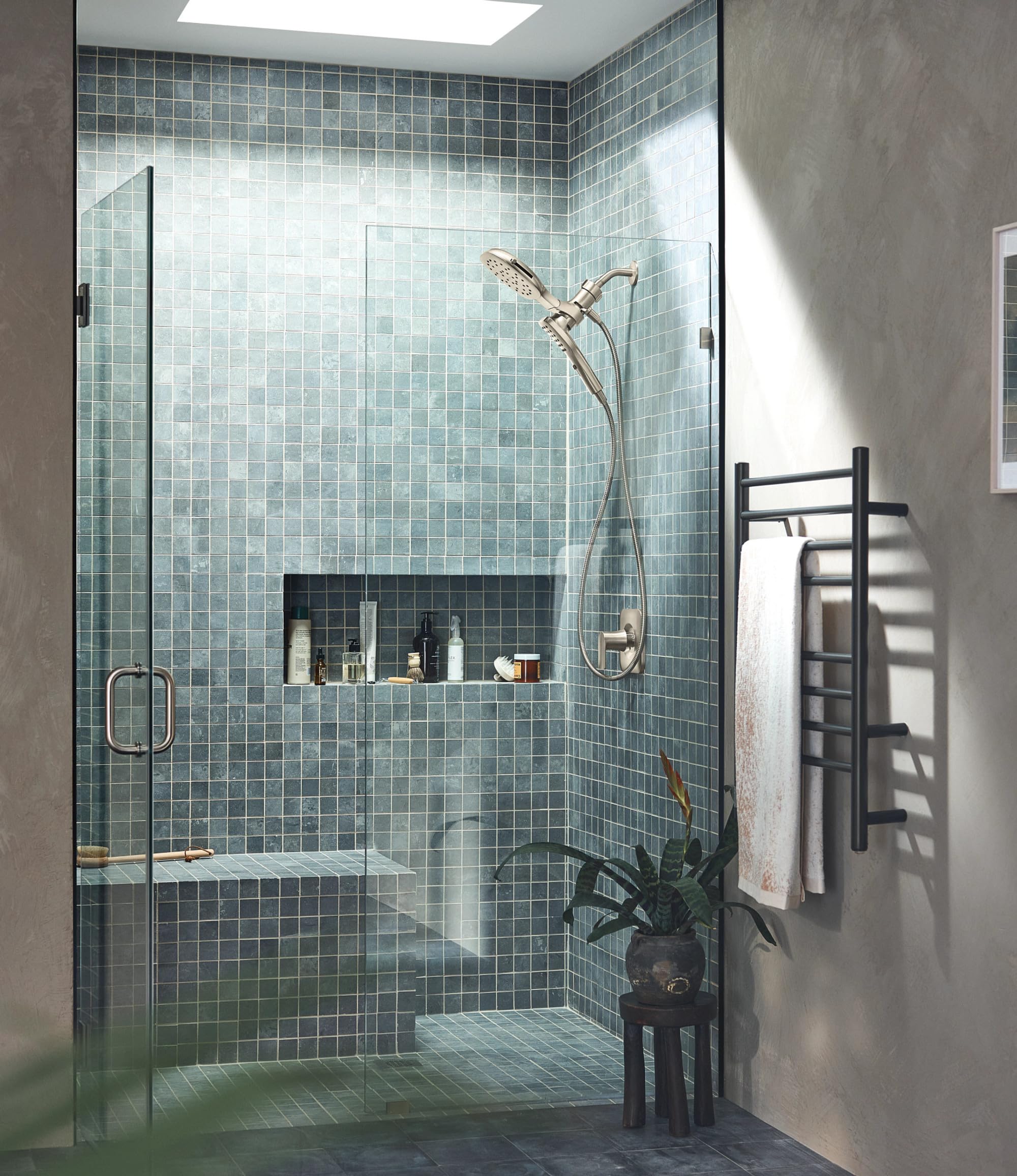 Brushed nickel shower head with detachable hand shower mounted in modern tiled shower enclosure.