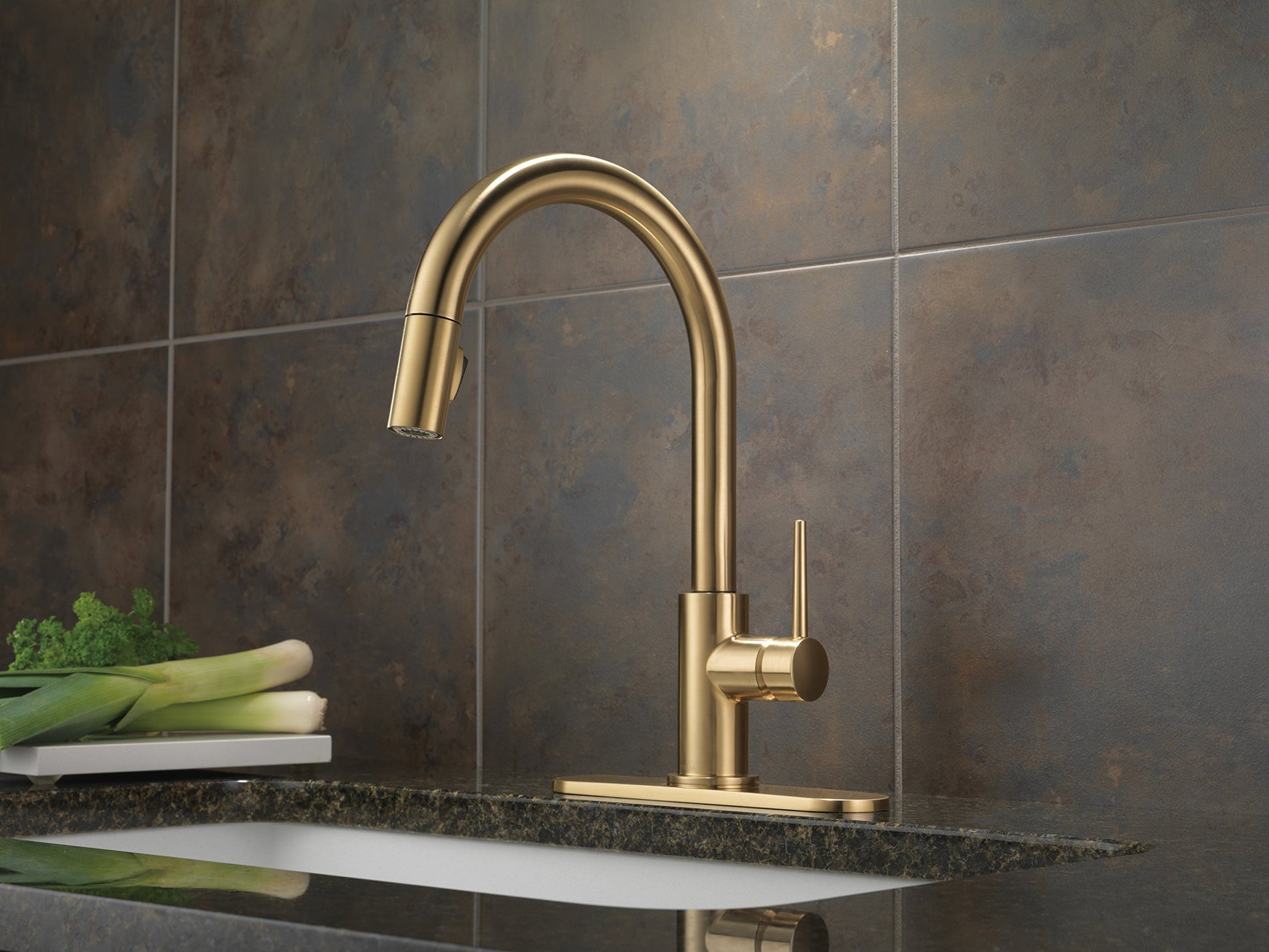 Champagne bronze kitchen faucet with pull-down sprayer and single lever handle mounted on countertop.