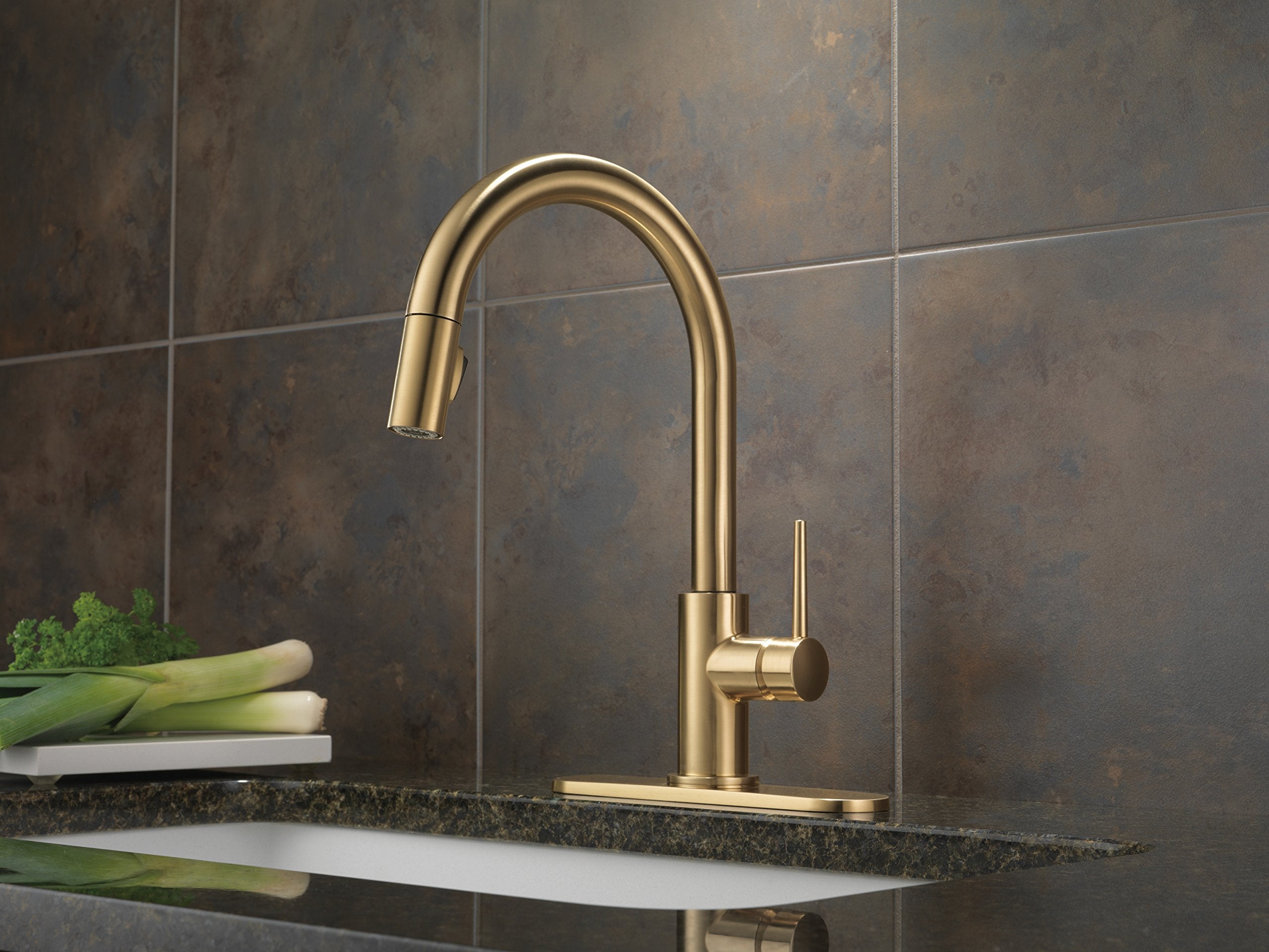 Champagne bronze kitchen faucet with pull-down sprayer and single lever handle mounted on countertop.