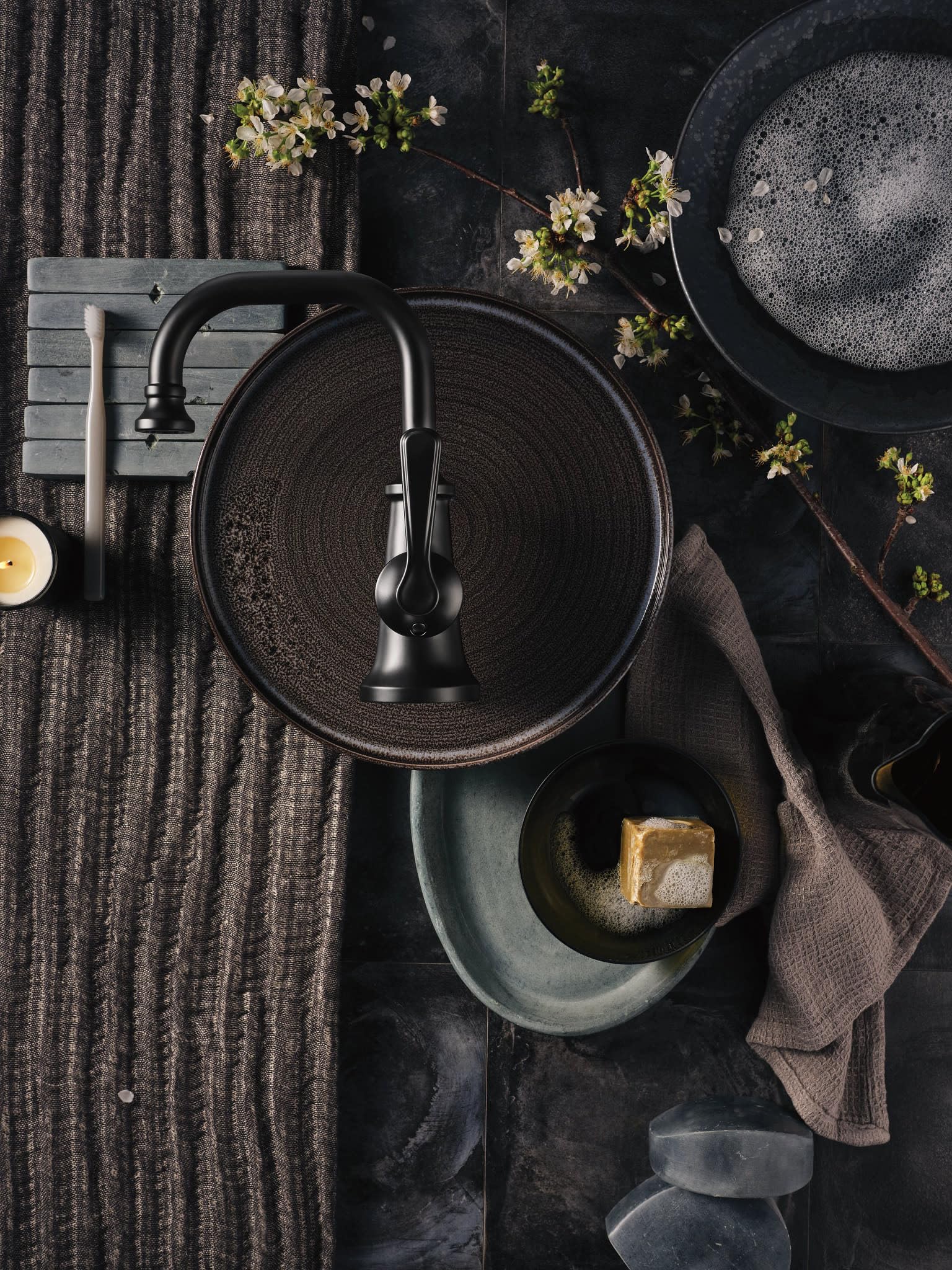 Matte black single-handle bathroom faucet with curved spout mounted above circular sink basin.