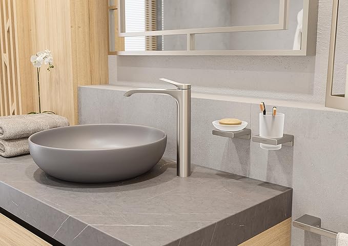 Brushed nickel soap dish with white ceramic interior mounted on gray bathroom countertop.
