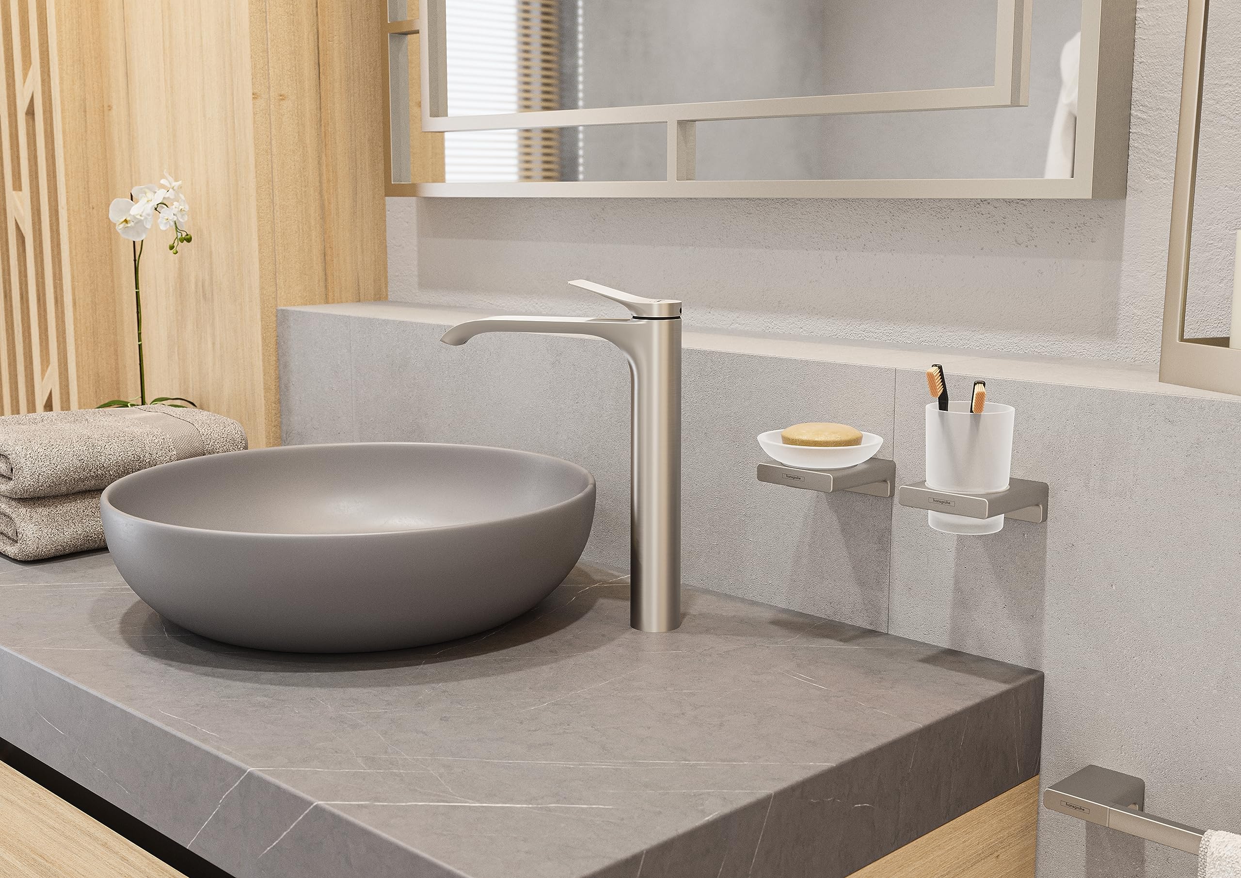 Brushed nickel cylindrical tumbler displayed on bathroom vanity counter next to matching faucet and accessories.