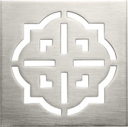 Burnished brass square drain trim grid with geometric cutout pattern and centered vertical slot.