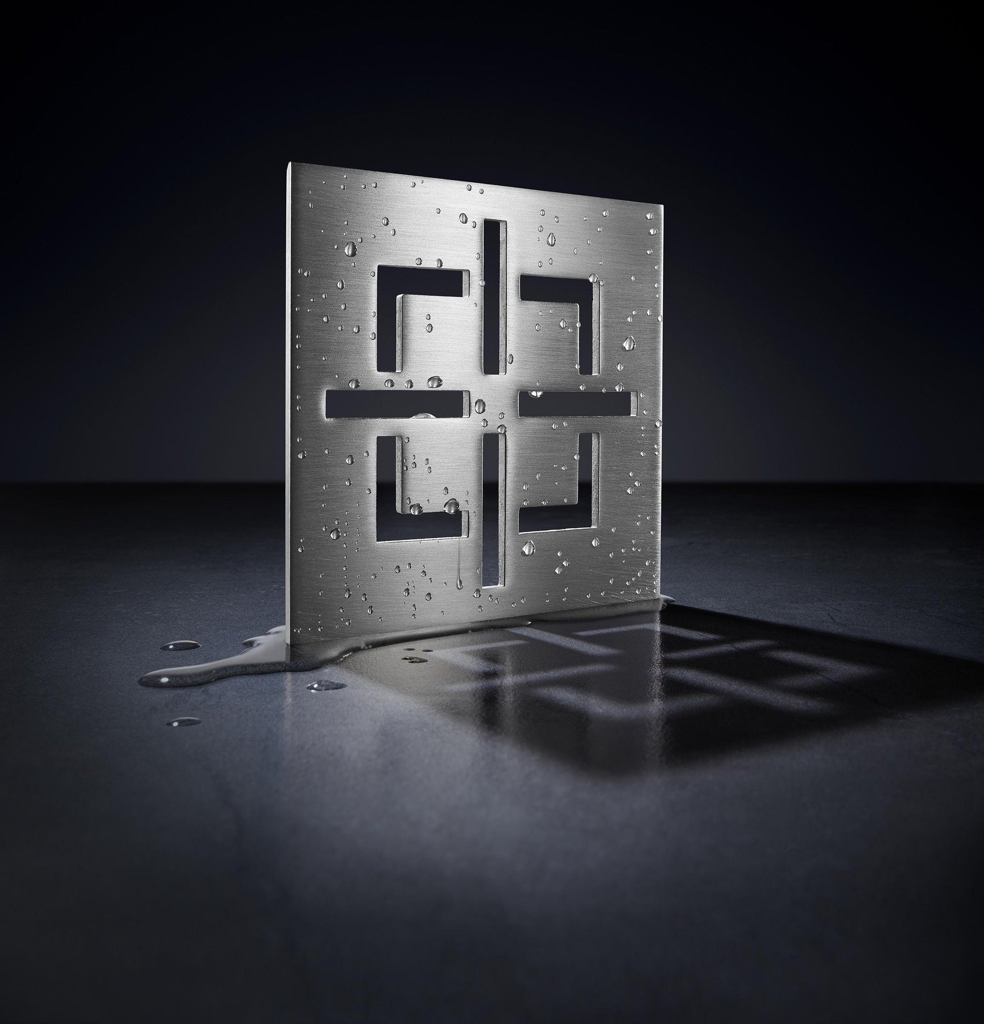 Satin brass drain trim grid with rectangular cutouts and mounting holes on perforated metal backing plate.