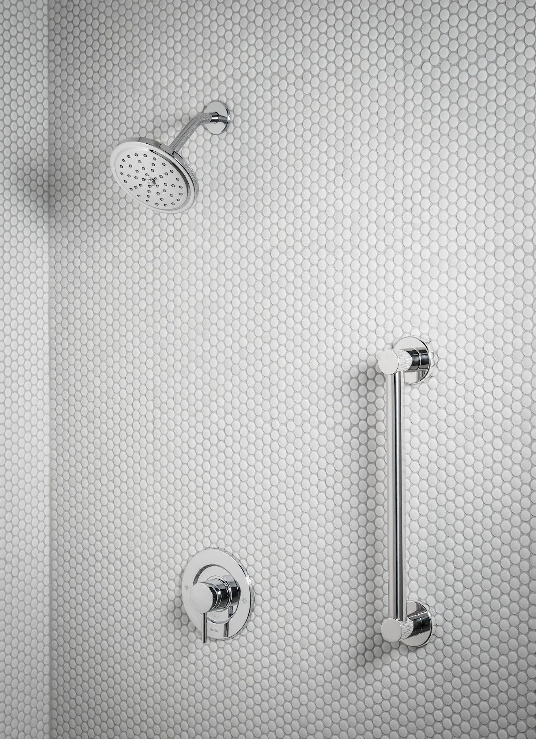 Chrome grab bar mounted vertically on bathroom wall next to shower fixtures and rainfall showerhead.