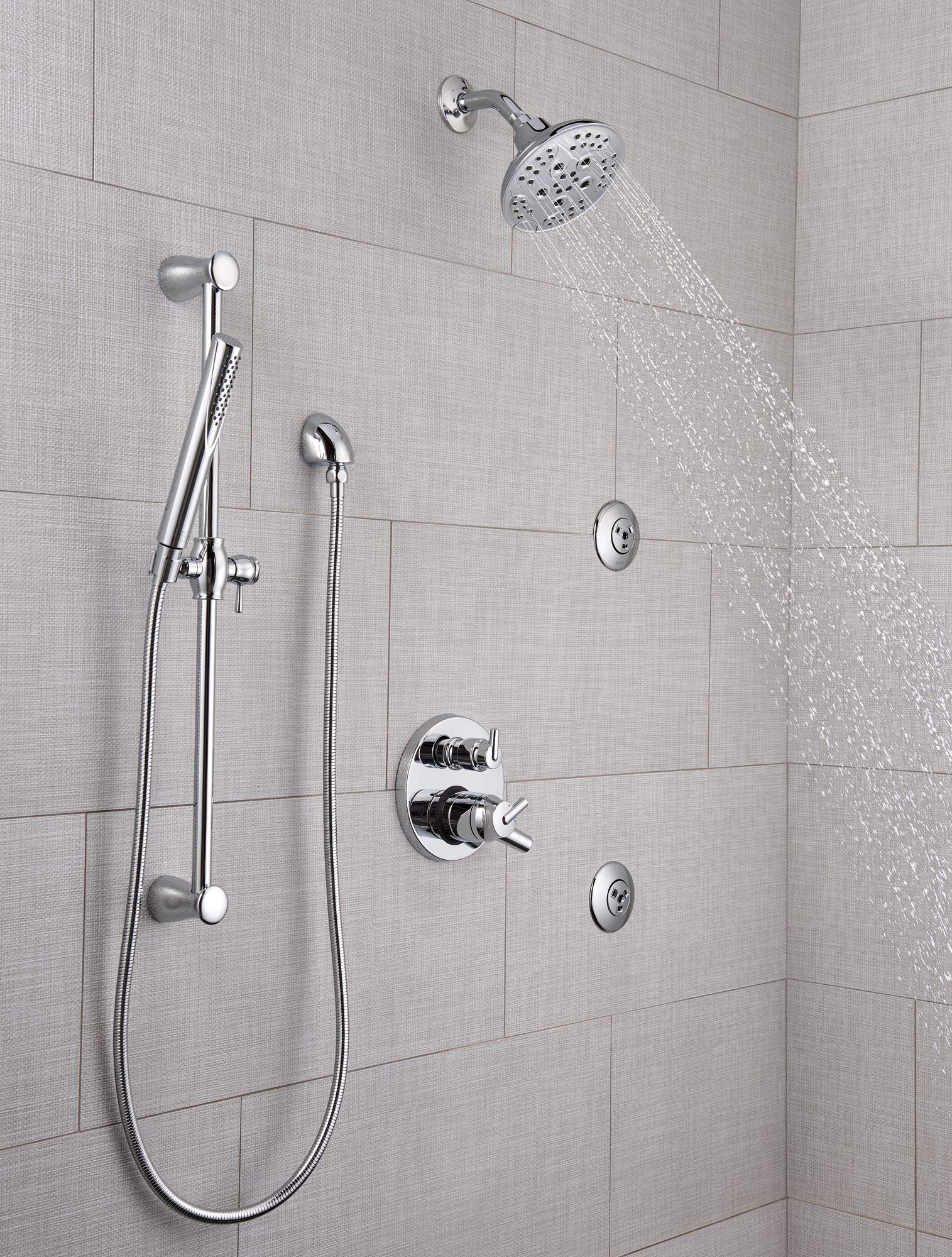Chrome shower system with overhead rainfall showerhead, handheld wand, and wall-mounted controls installed in tiled bathroom.