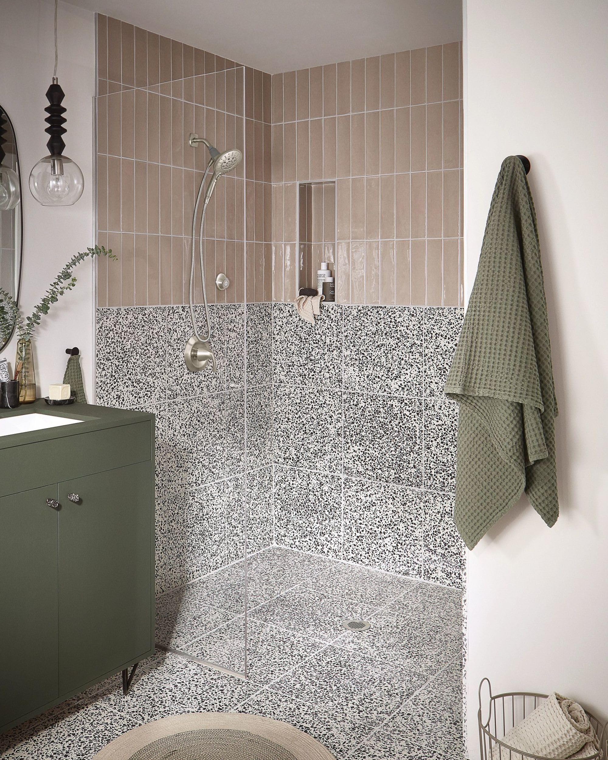 Brushed nickel showerhead dock mounted on shower wall above terrazzo tile surround.