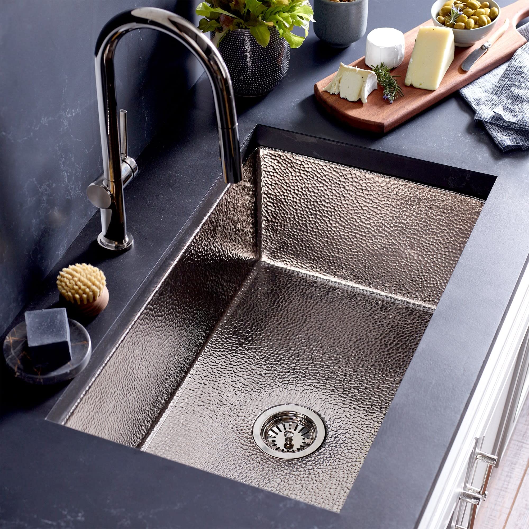 Brushed nickel 30" single-bowl kitchen sink with hammered texture, drain, and matching faucet installed in dark countertop.