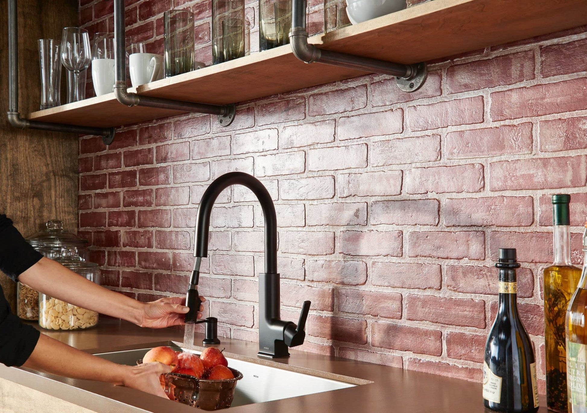 Matte black countertop soap and lotion dispenser displayed on kitchen counter next to sink.